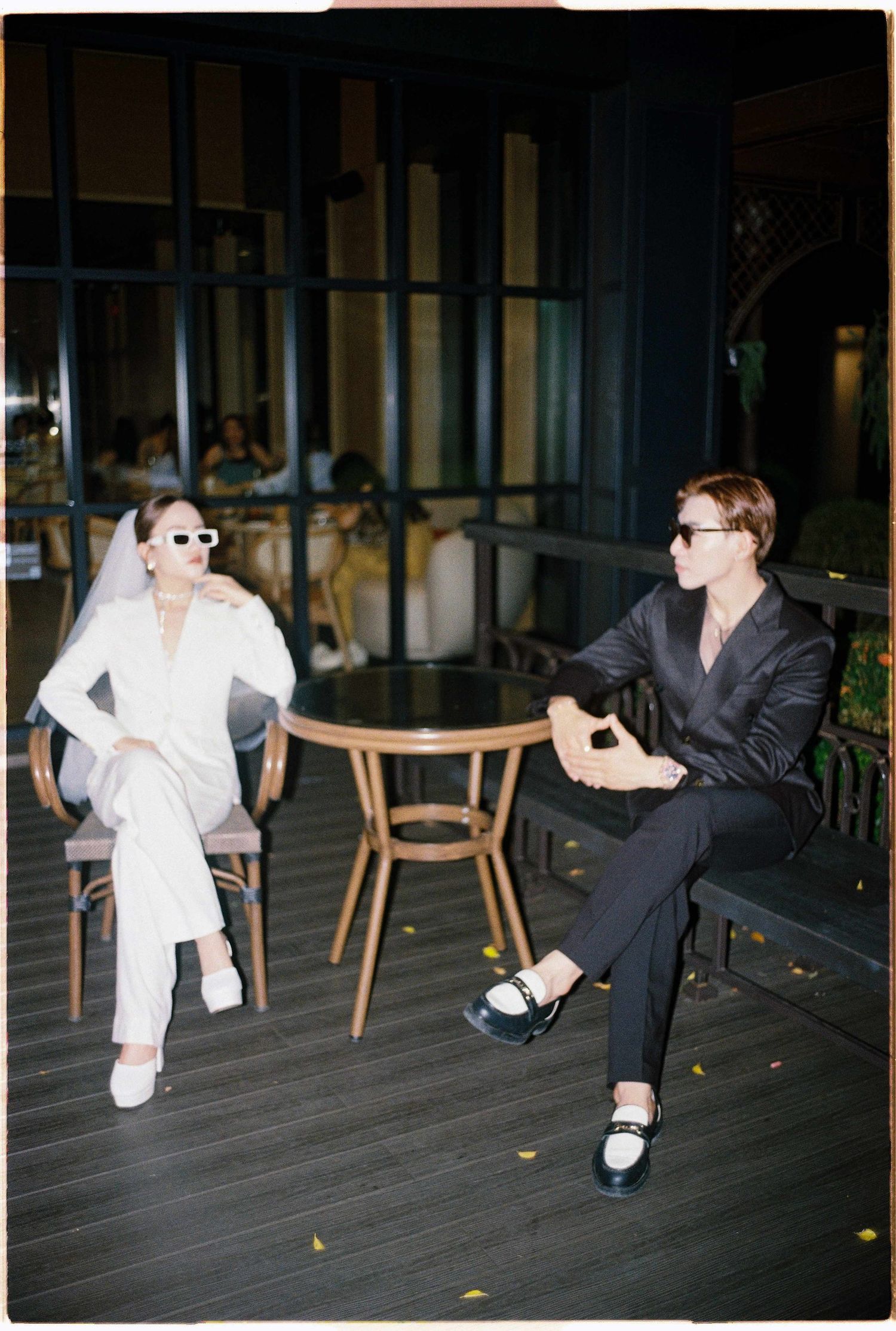 Saigon pre-wedding: two people in contrasting outfits sit casually on an outdoor deck, by AnhVuWedding.