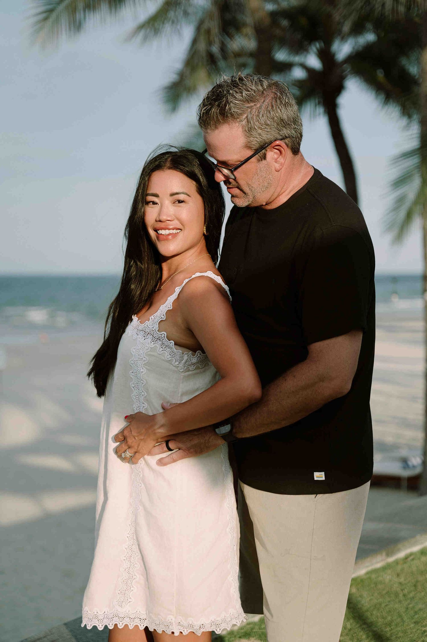 Da Nang family: couple embraces on a scenic beachfront, by AnhVuWedding.