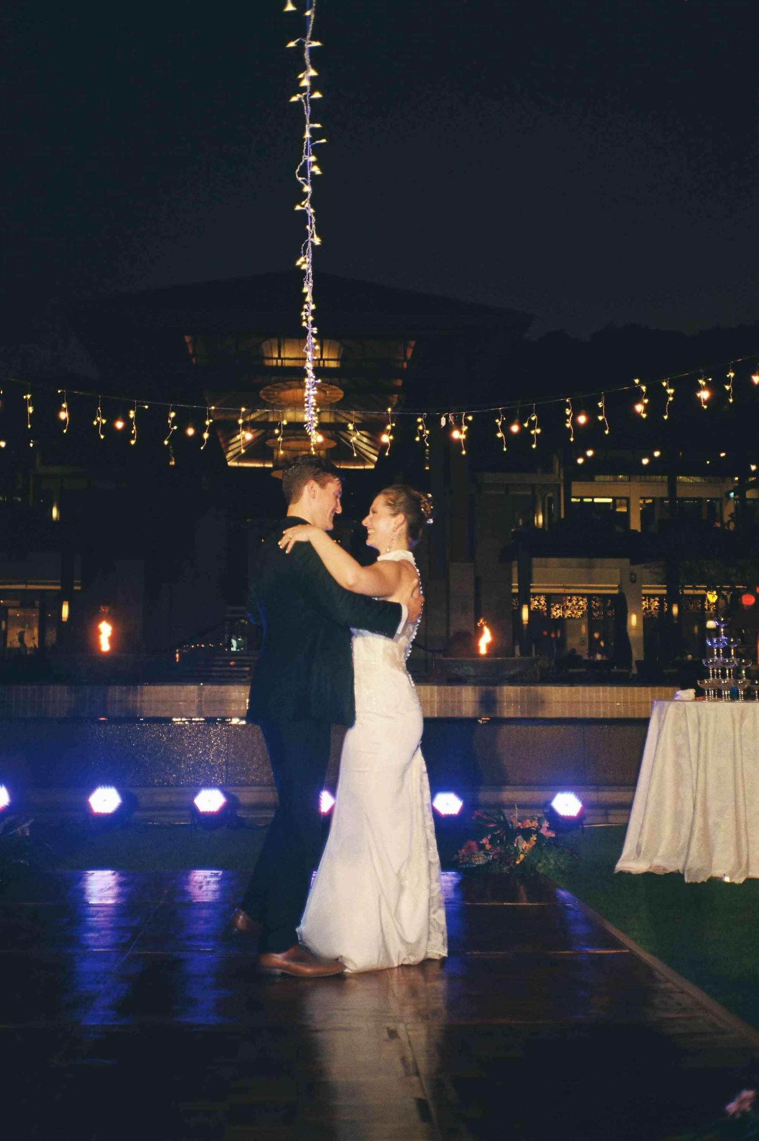 Lang Co wedding: wedding dance performance on an outdoor patio illuminated by purple spotlights and string lights, by AnhVuWedding.
