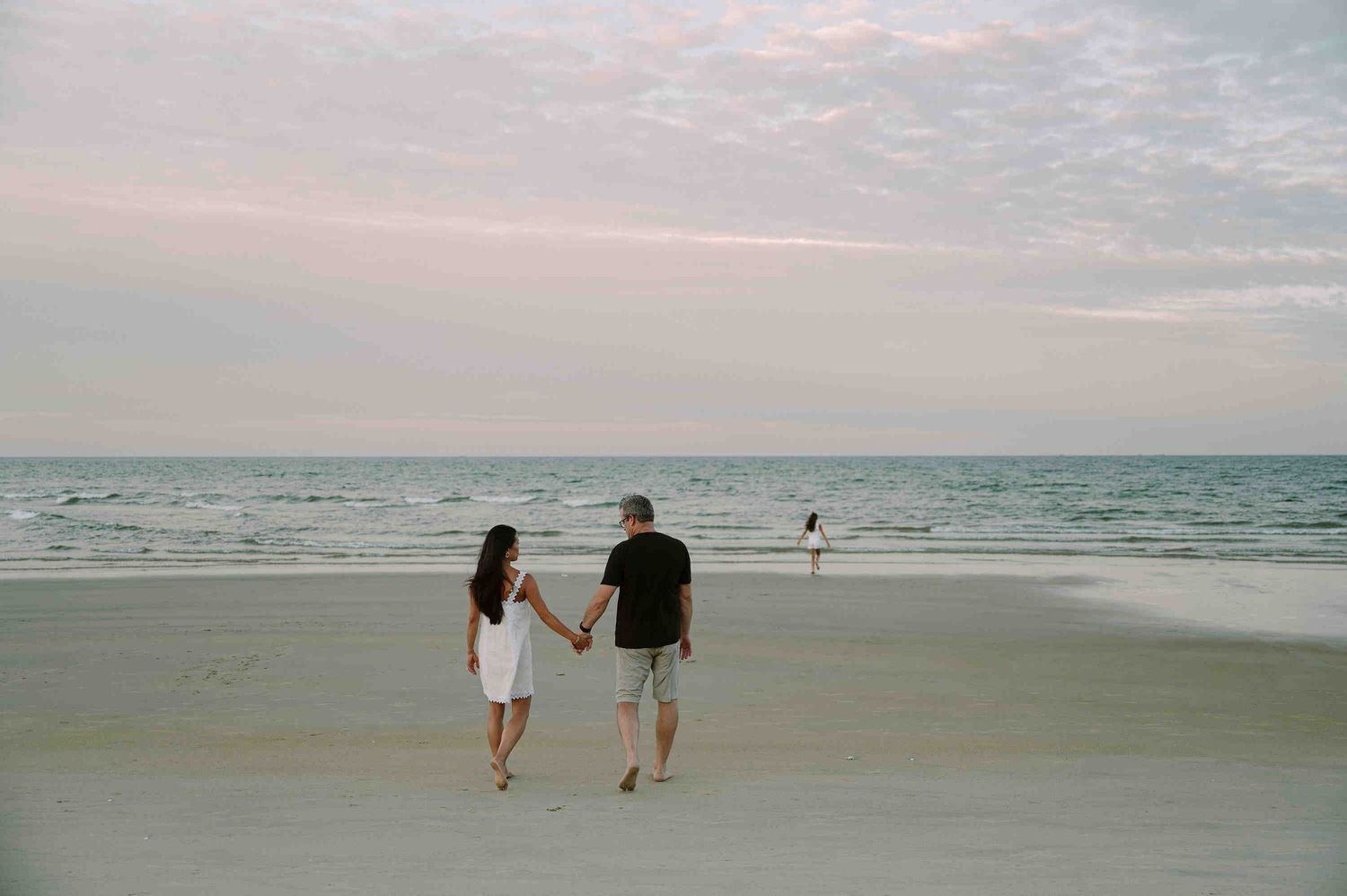 Da Nang family: two people walking together on a serene beach at sunset, by AnhVuWedding.
