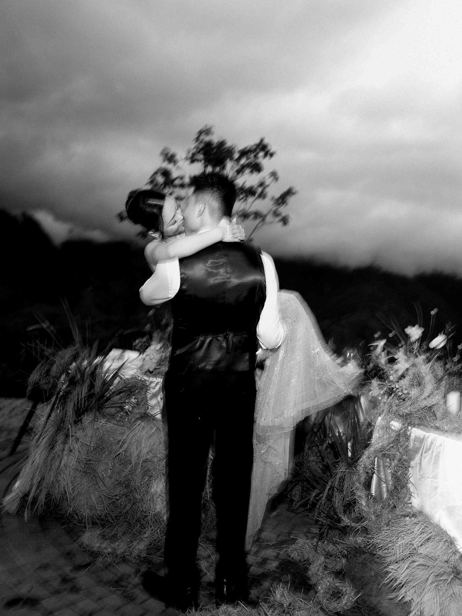 wedding: dramatic black and white wedding photo series showing a couple in formal attire against a moody sky, by AnhVuWedding.
