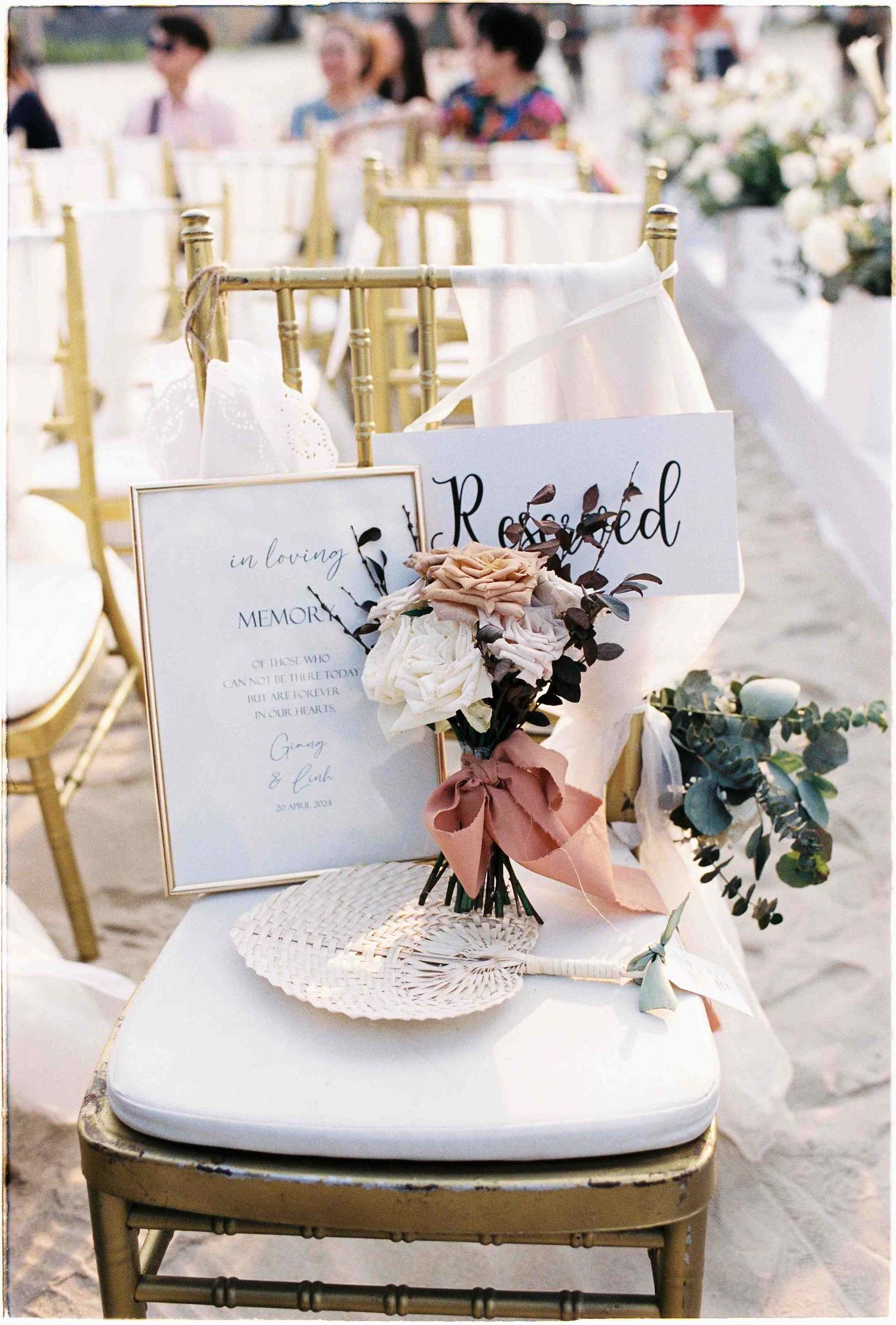 Reserved wedding ceremony chair with bouquet of white and blush flowers beside an in loving memory memorial sign.
