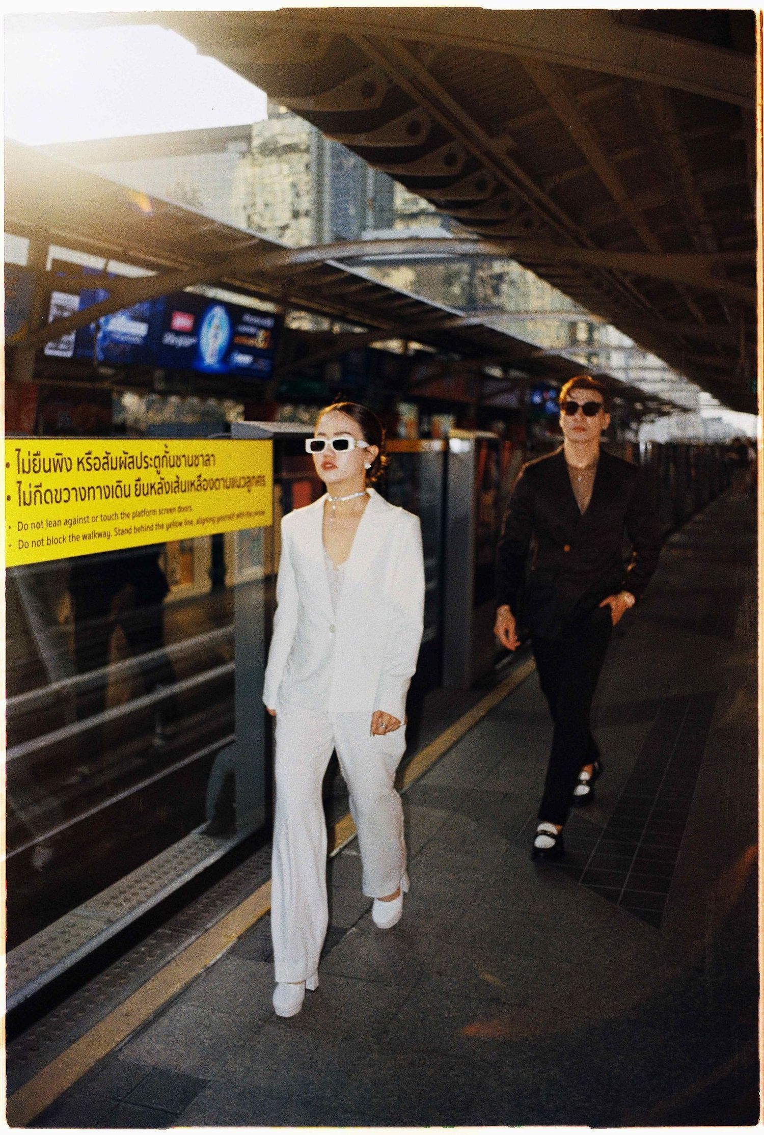 Saigon pre-wedding: two people in contrasting black and white outfits walk through a transit station, by AnhVuWedding.