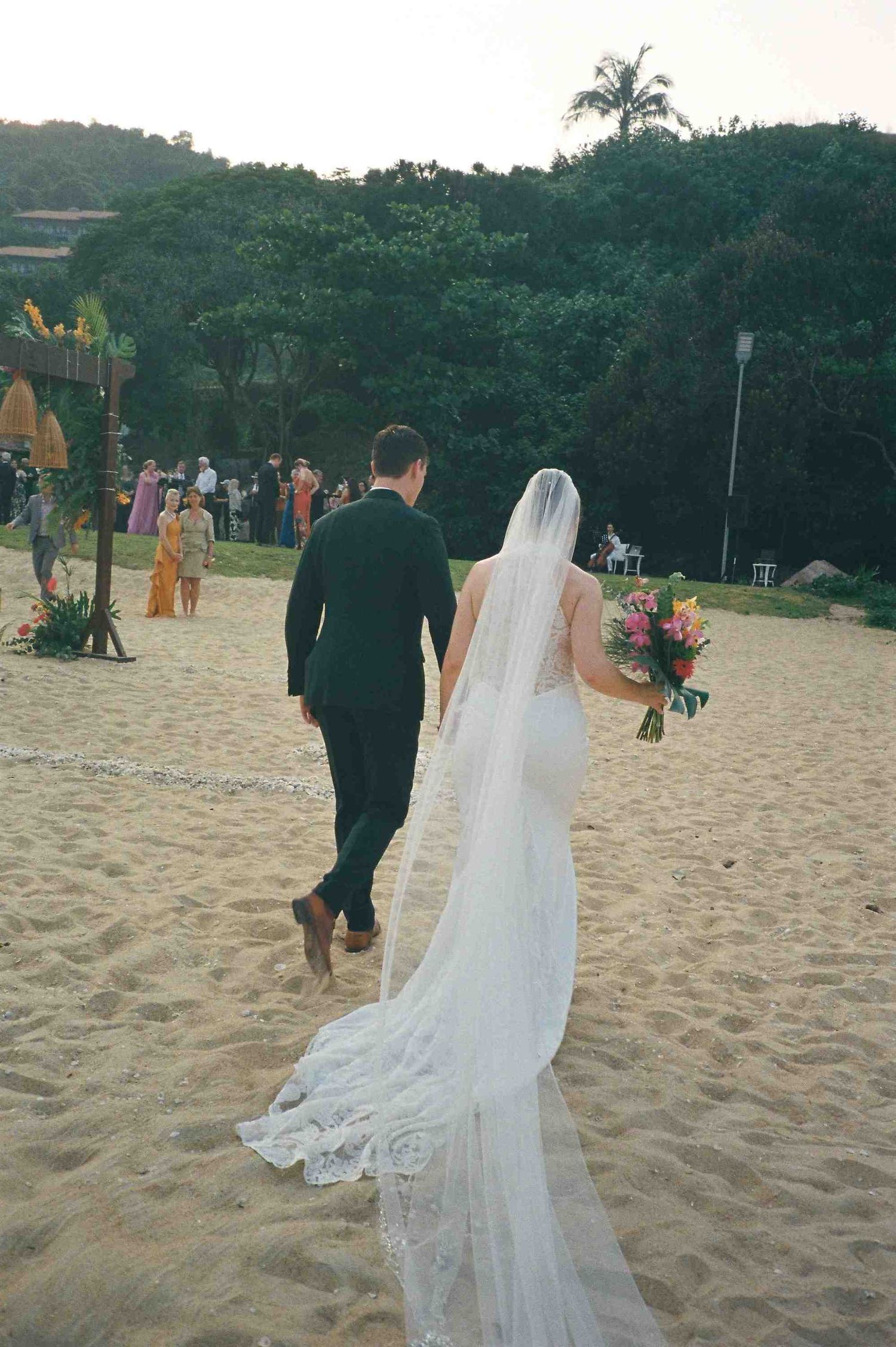 Lang Co wedding ceremony: newlyweds walk along sandy beach path after sunset ceremony, by AnhVuWedding.