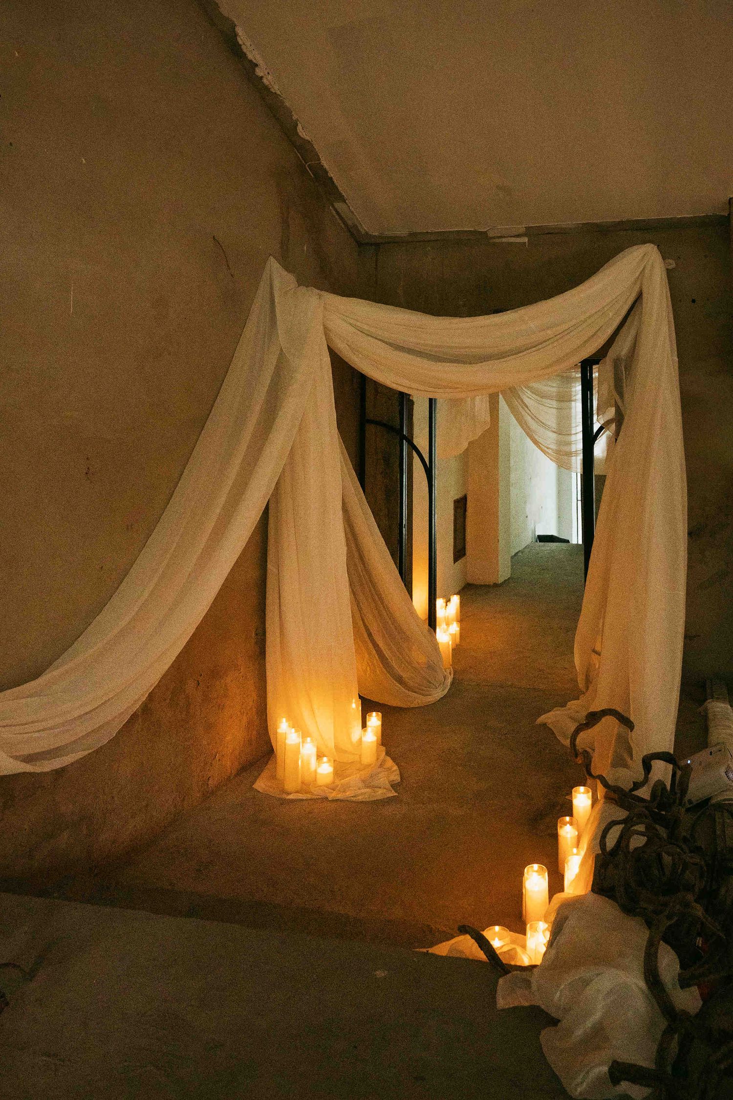 Romantic hallway with white draped fabric and glowing candles creating an elegant, dreamy ambiance.