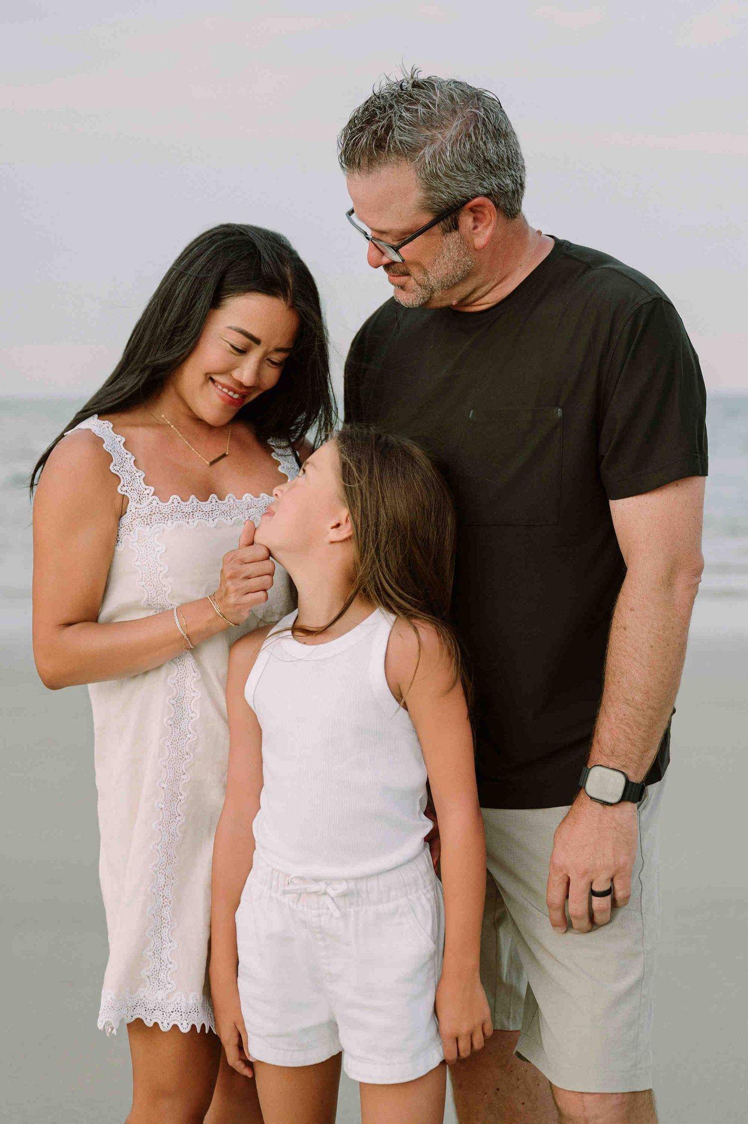 Da Nang family: family shares tender moments together at the beach, wearing casual white and black clothing, by AnhVuWedding.