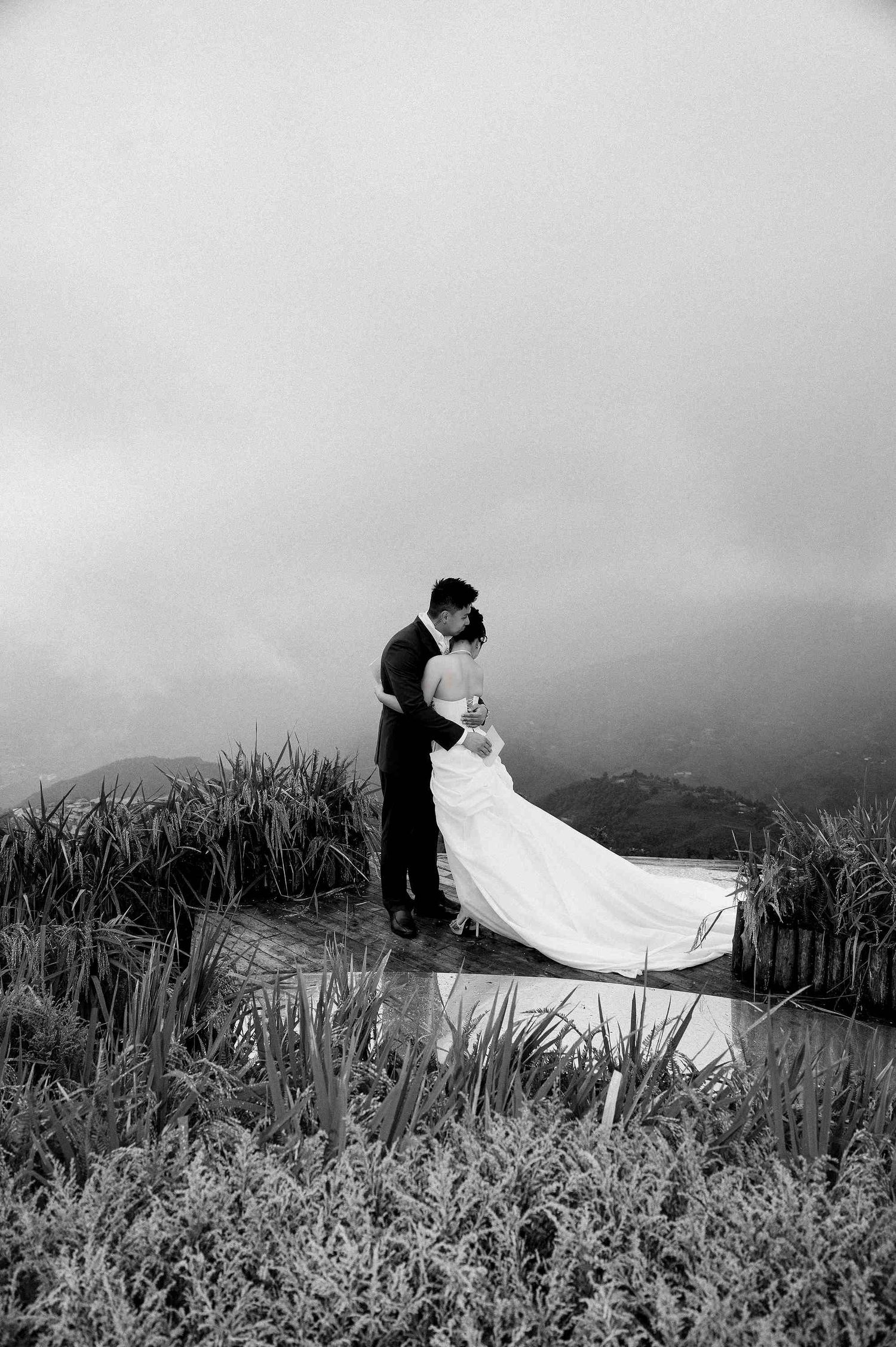 wedding: dramatic black and white wedding photos with couple posing among tall grass on mountainside, by AnhVuWedding.