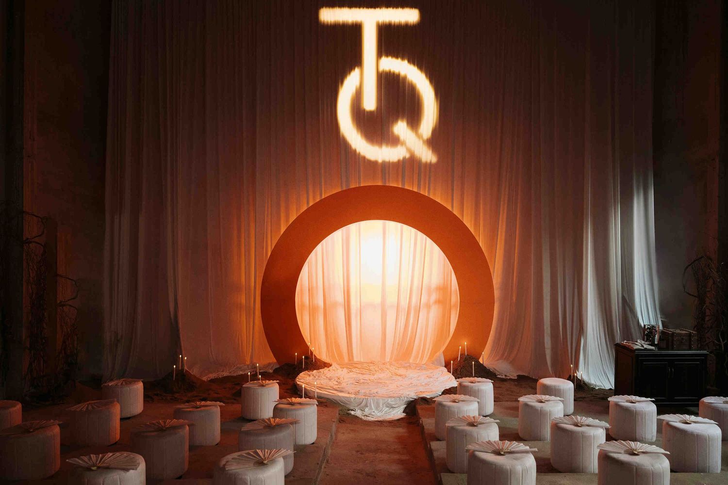 Da Nang wedding ceremony: elegant event setup with glowing TQ monogram sign above an orange arch, white drapes, by AnhVuWedding.