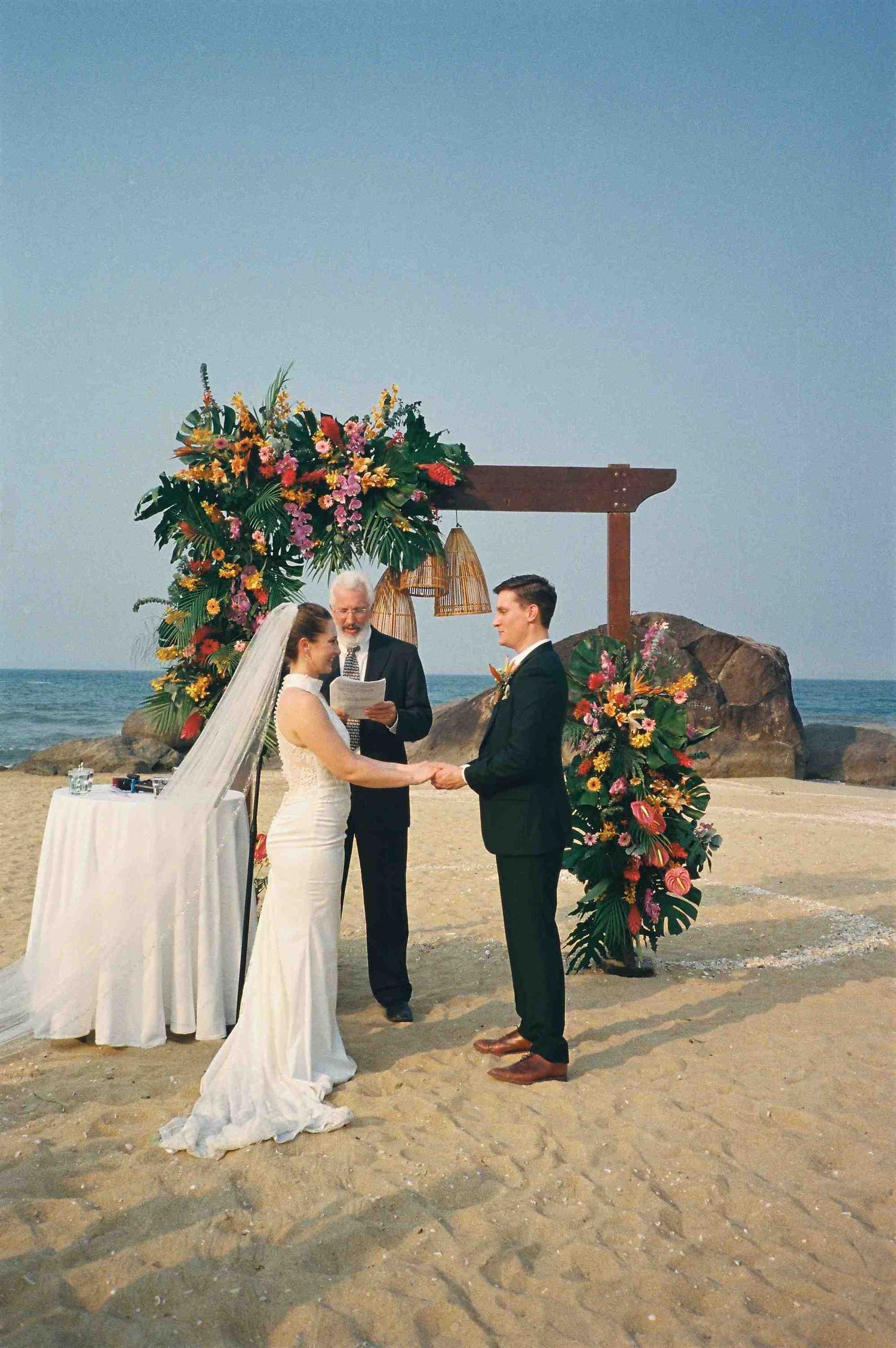 Lang Co wedding ceremony: intimate beach wedding ceremony with ocean backdrop and tropical flower arrangements, by AnhVuWedding.