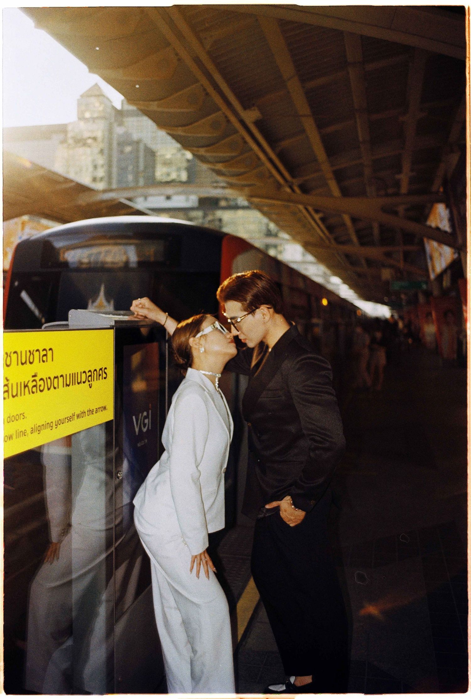 Saigon pre-wedding: couple in contrasting outfits shares an intimate moment at a transit station, by AnhVuWedding.