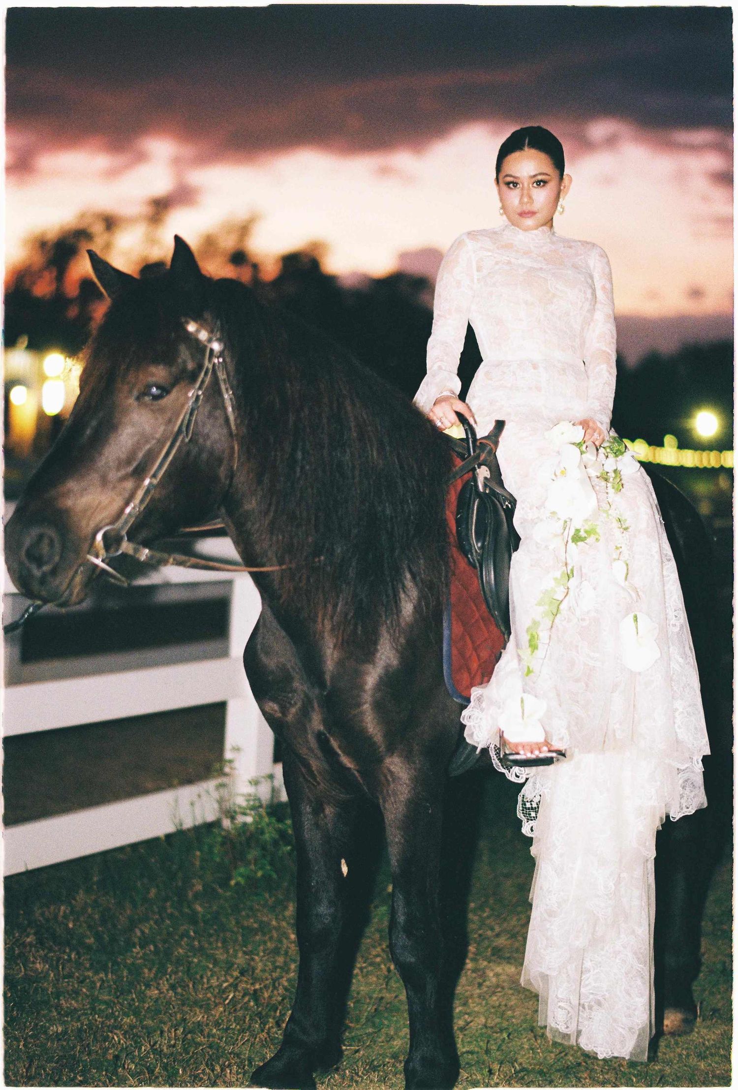 Saigon pre-wedding: figure in an elegant white lace dress poses with a dark horse, by AnhVuWedding.