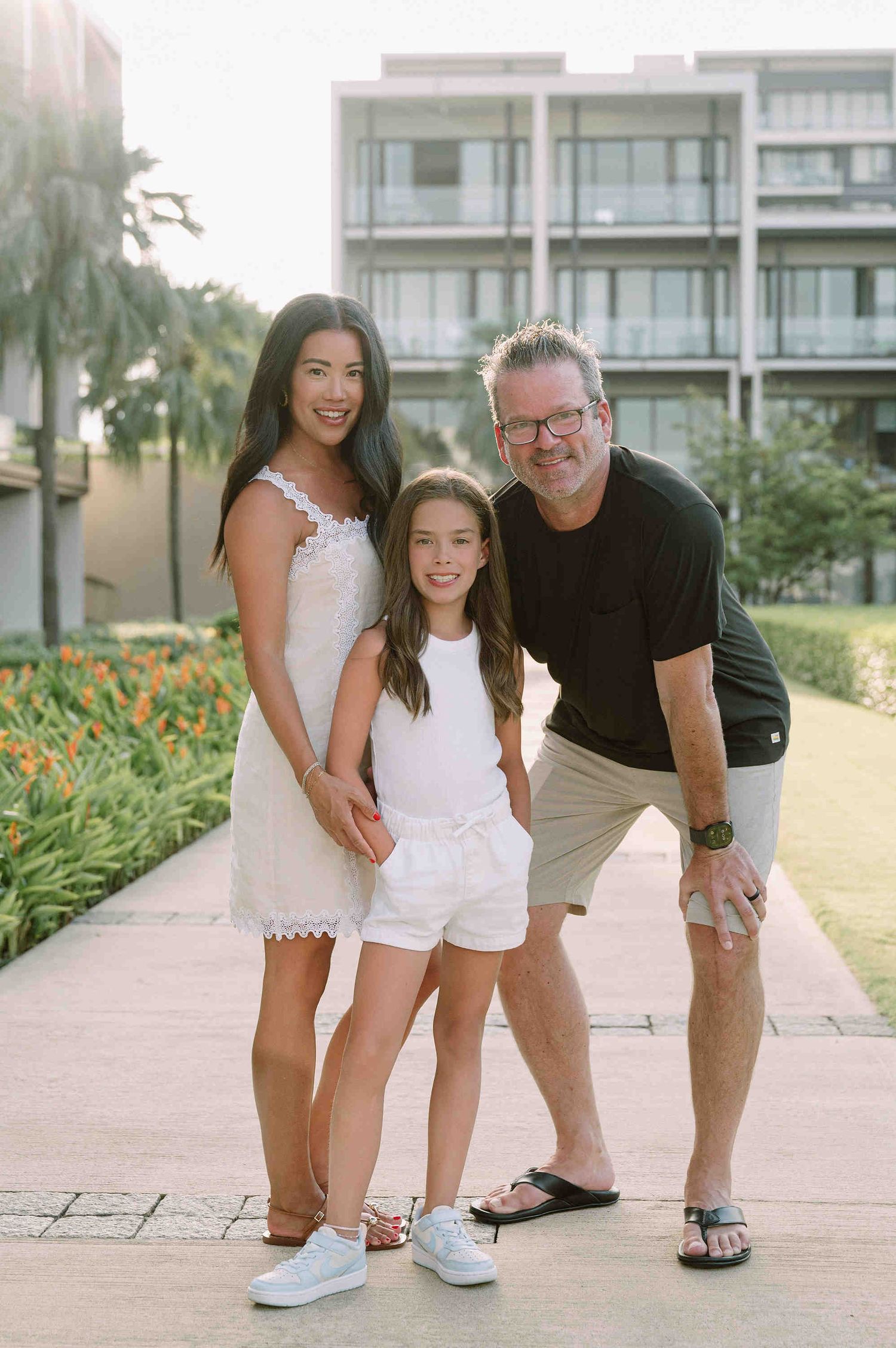 Da Nang family: family wearing white and black outfits poses together outdoors in a series of candid shots, by AnhVuWedding.