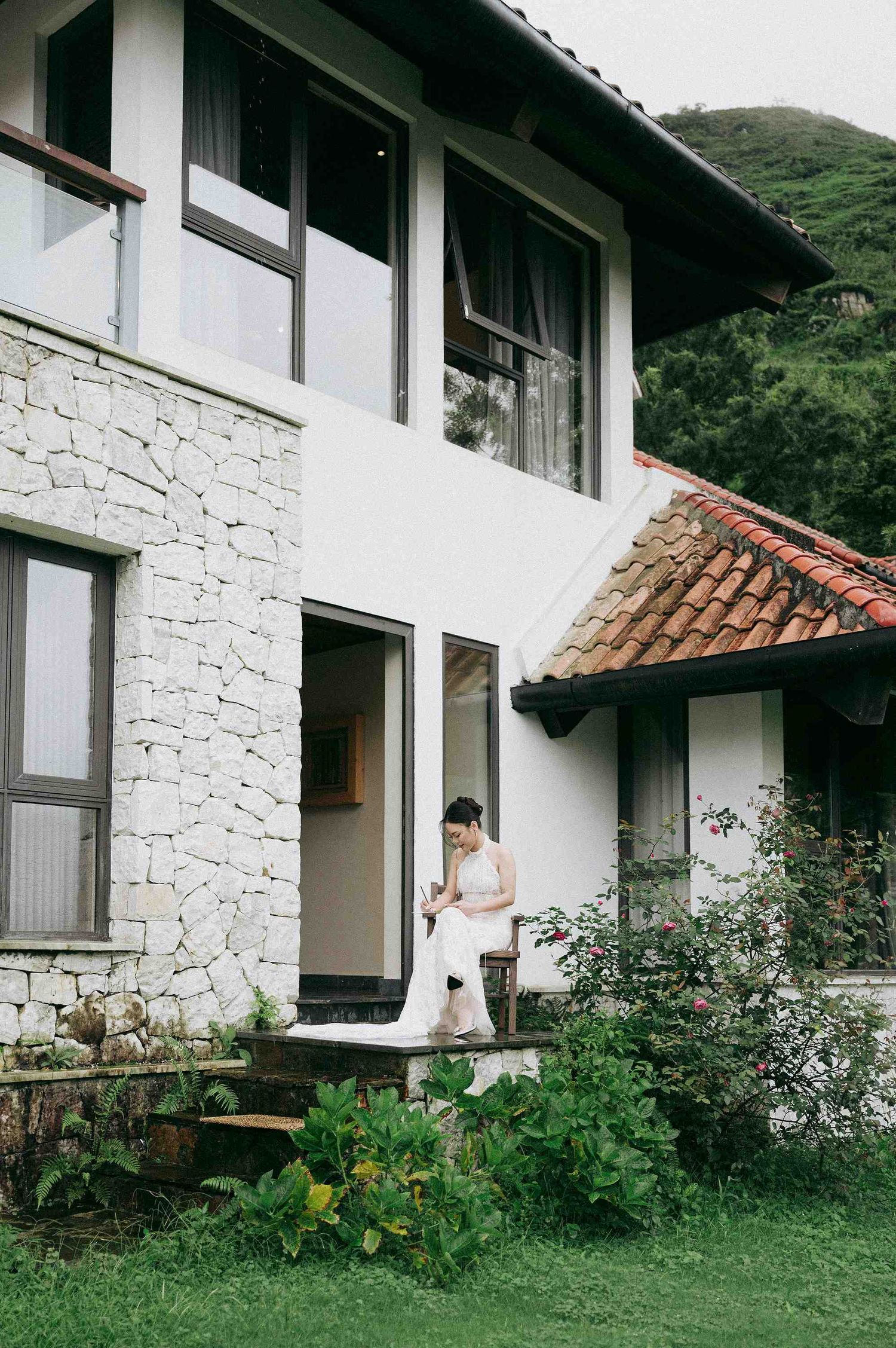wedding: modern white house with stone walls and terrace surrounded by garden plants in a mountainous setting, by AnhVuWedding.