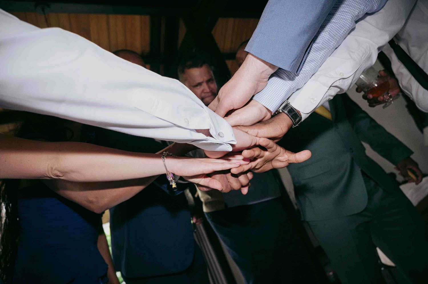 Group of people joining hands together in a team unity gesture at a formal event or wedding celebration.