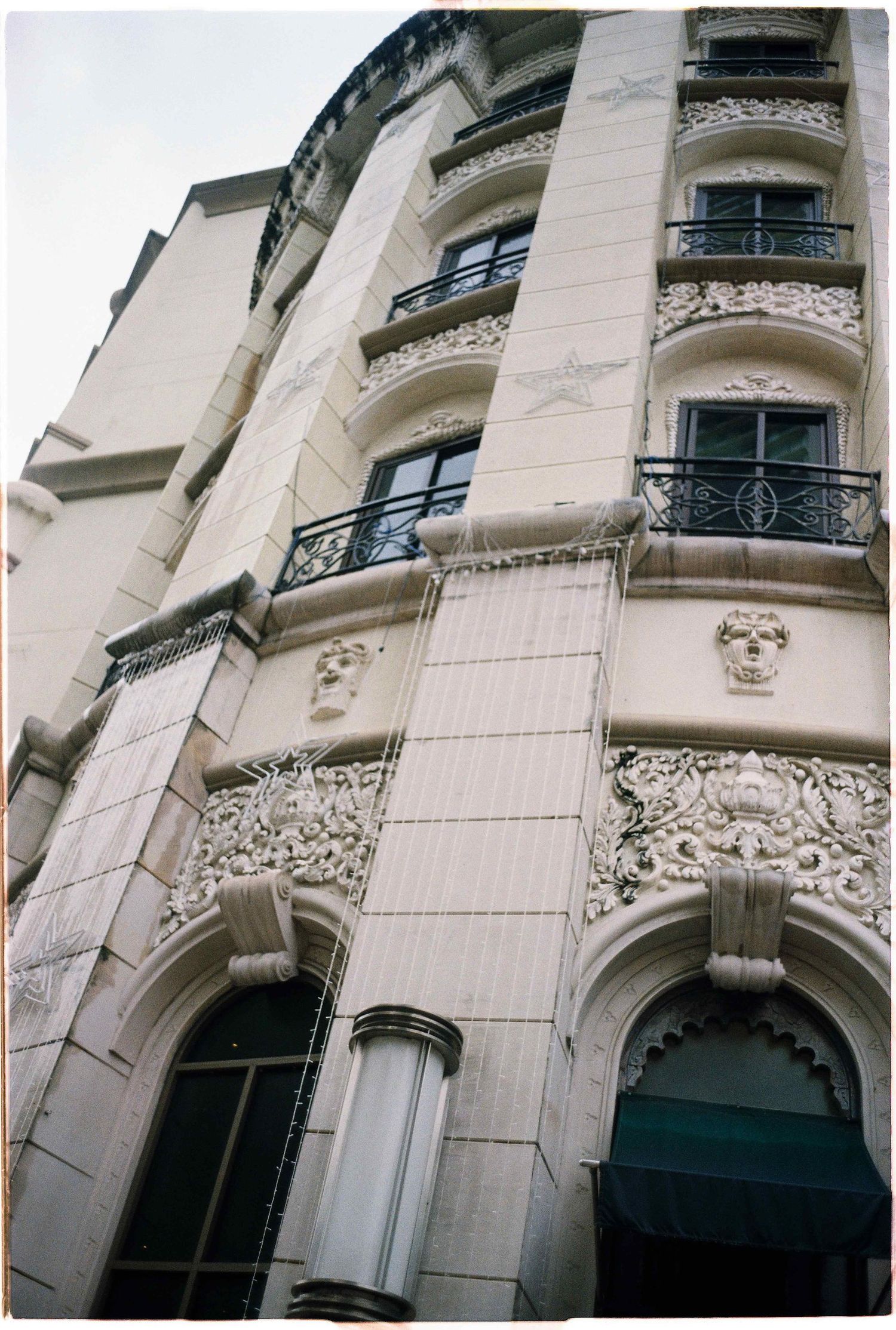 Saigon pre-wedding: ornate white building facade with decorative balconies and architectural details shot from below, by AnhVuWedding.