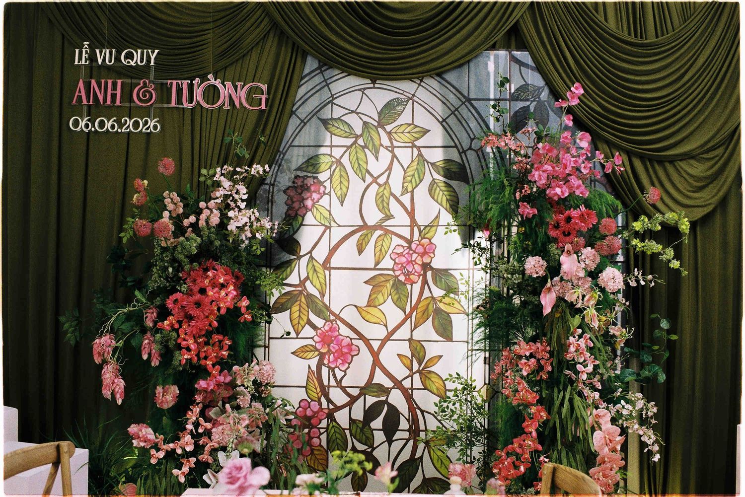 Vietnamese wedding backdrop with pink floral arch, stained glass window, and green drapes for Le Vu Quy ceremony on 06.06.2025.