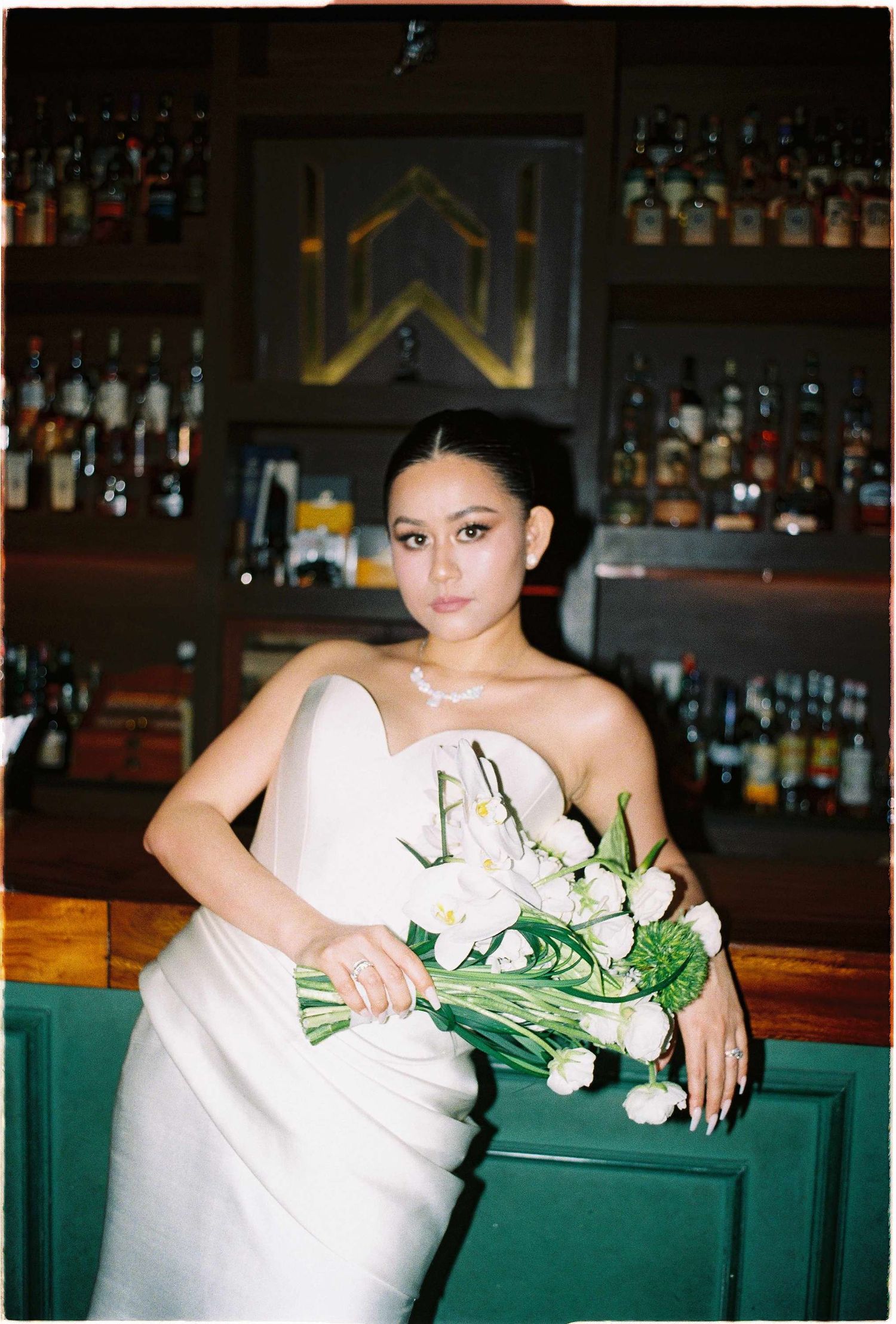 Vietnam pre-wedding: elegant wedding photography session at dimly lit bar with floral arrangements, by AnhVuWedding.