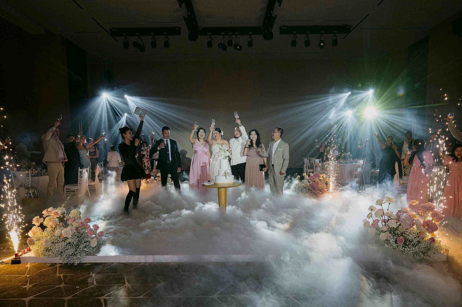 Shilla Da Nang wedding ceremony: wedding celebration with fog machines and light beams creating dramatic atmosphere, by AnhVuWedding.