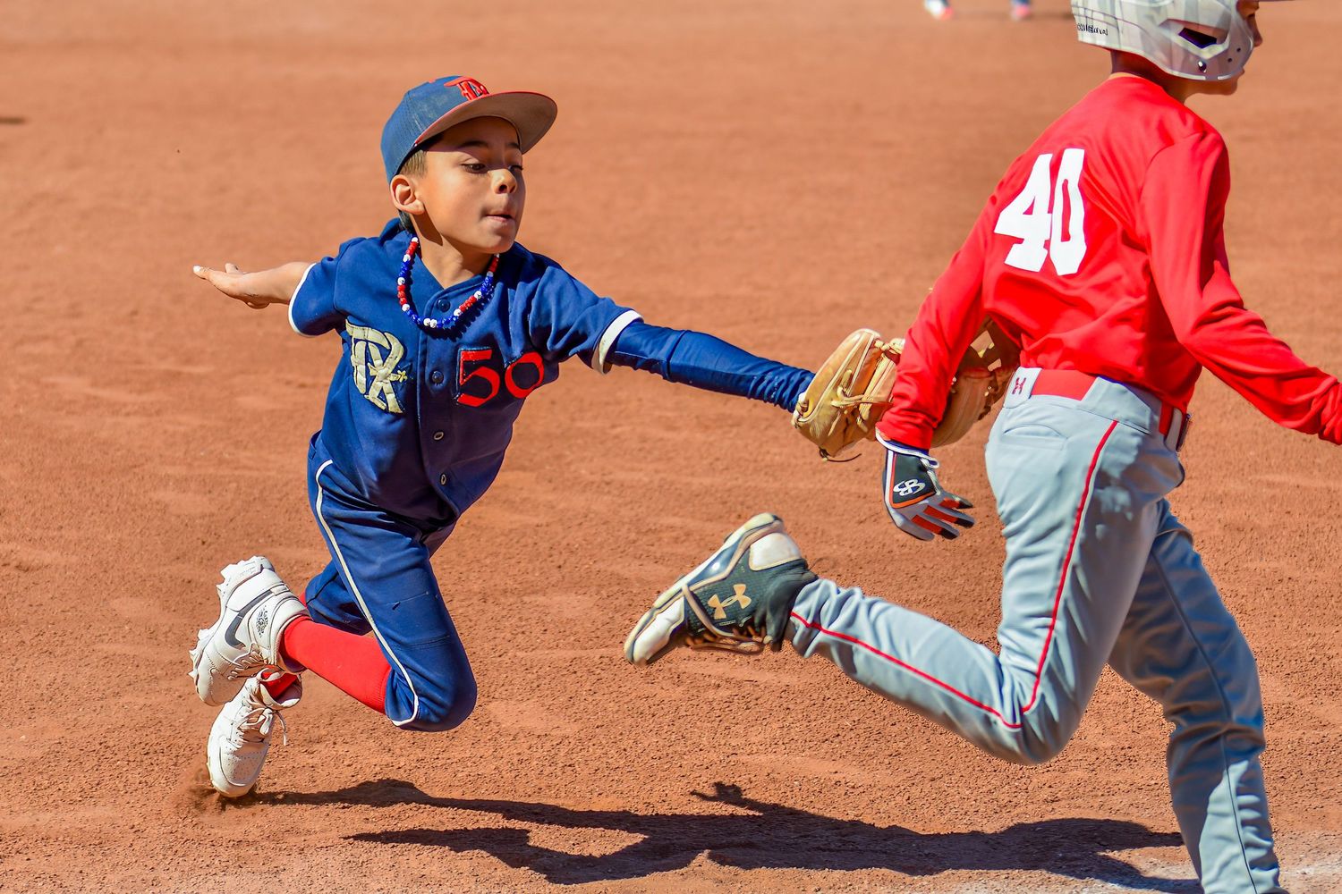 Two young baseball players collide as a fielder tags out a runner during a little league game.