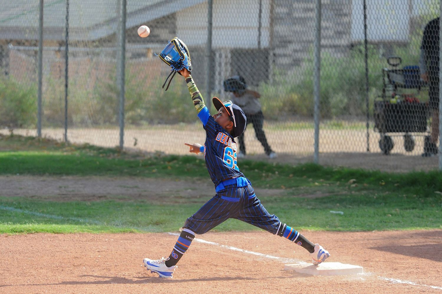 Young baseball player in blue uniform making powerful swing at pitch during youth baseball game outdoors.