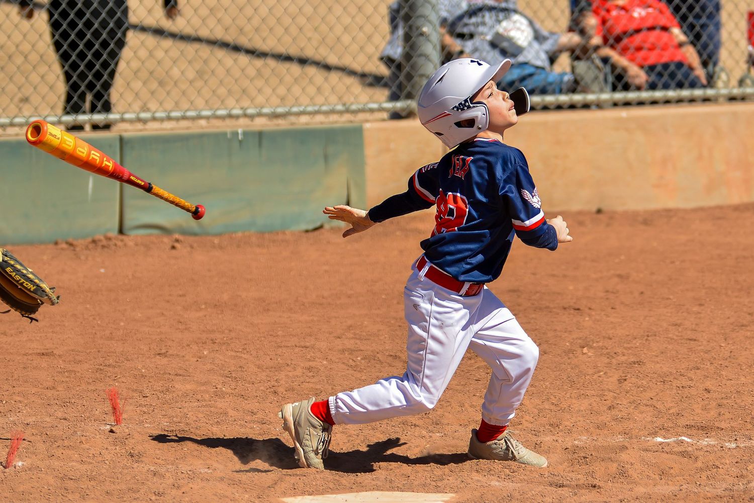 Young baseball player drops bat while running after making contact during a youth league game.