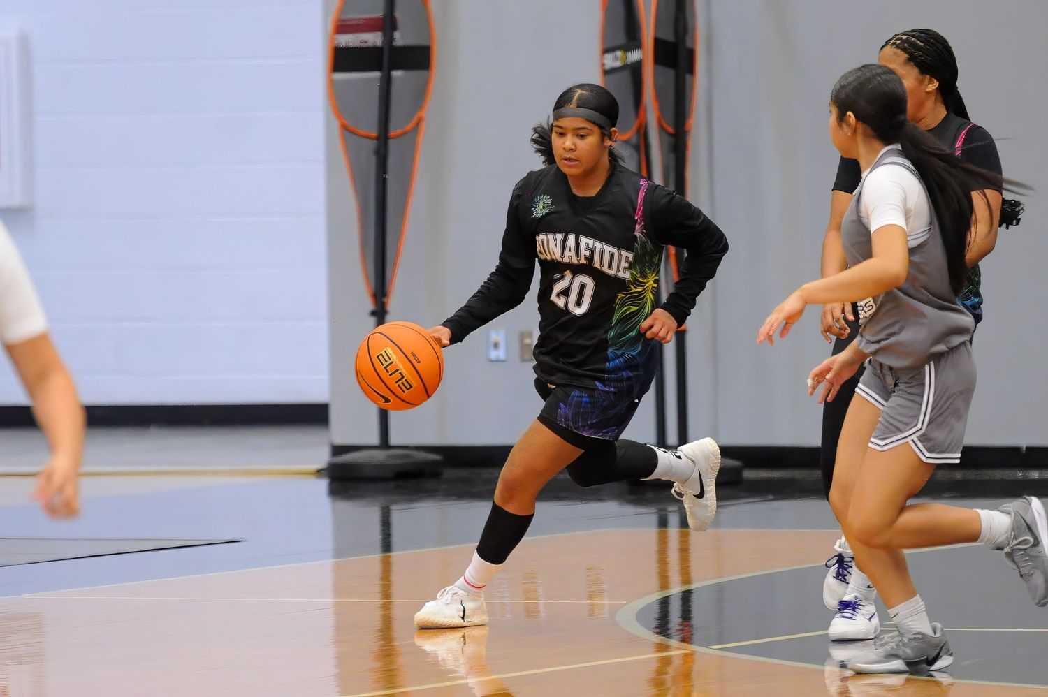 Female basketball player #20 in black Bonafide uniform dribbles during indoor practice game.