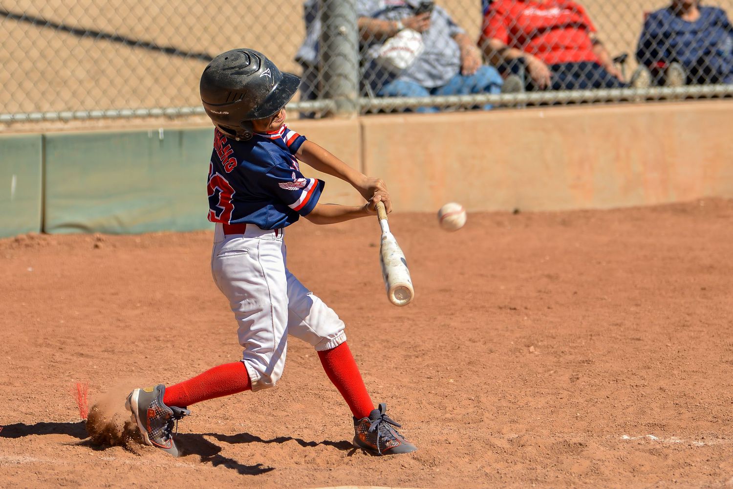 Young baseball player makes contact with the ball during a youth little league game.