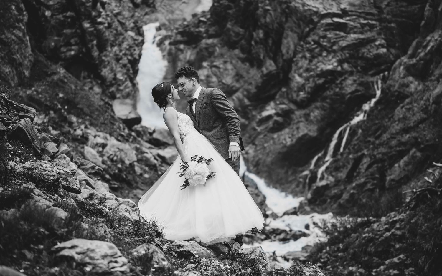 Hochzeitspaar vor Wasserfall in den Bergen in Schwarzweiss