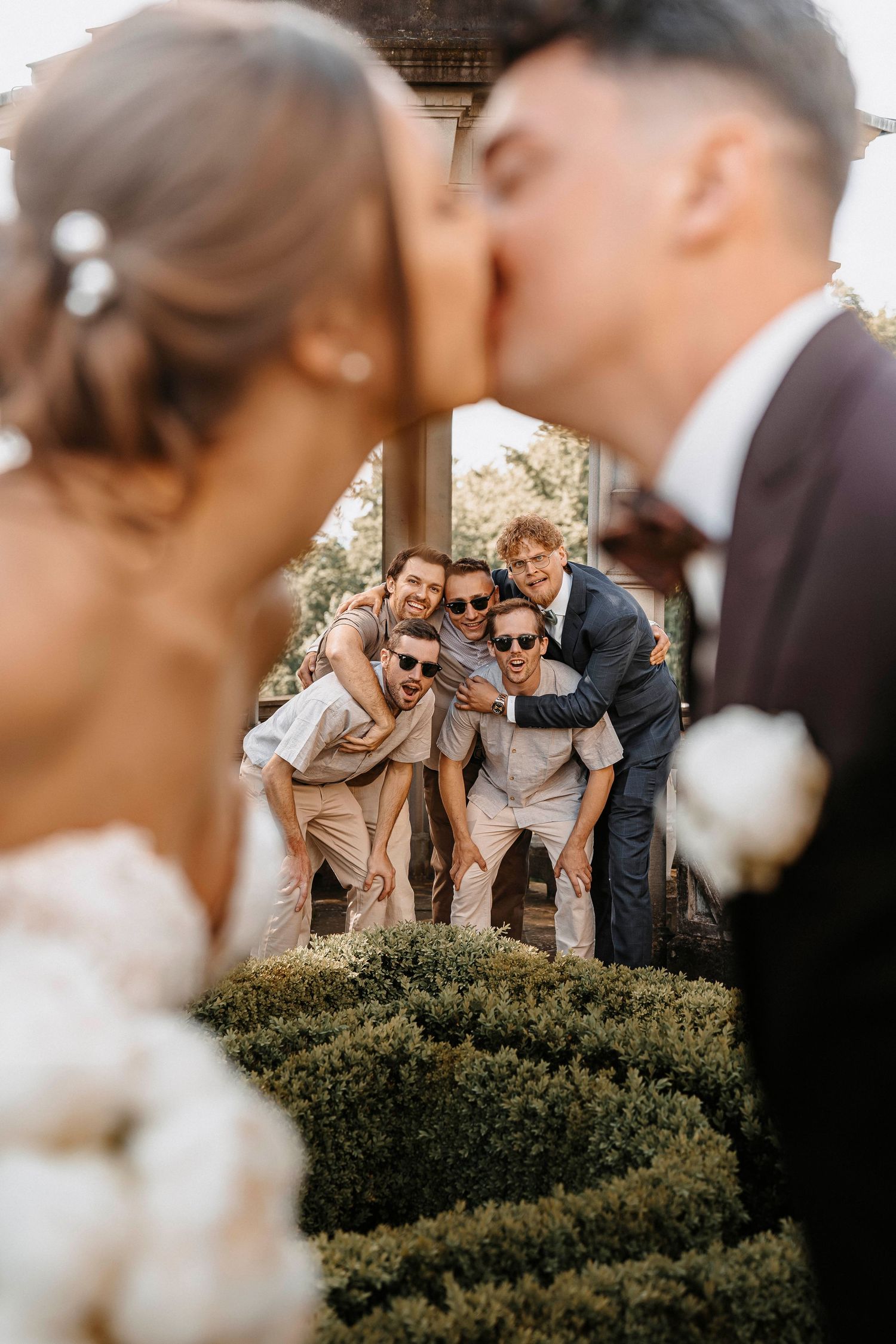 Kuss des Brautpaares während der Hochzeit mit Gästen im Hintergrund