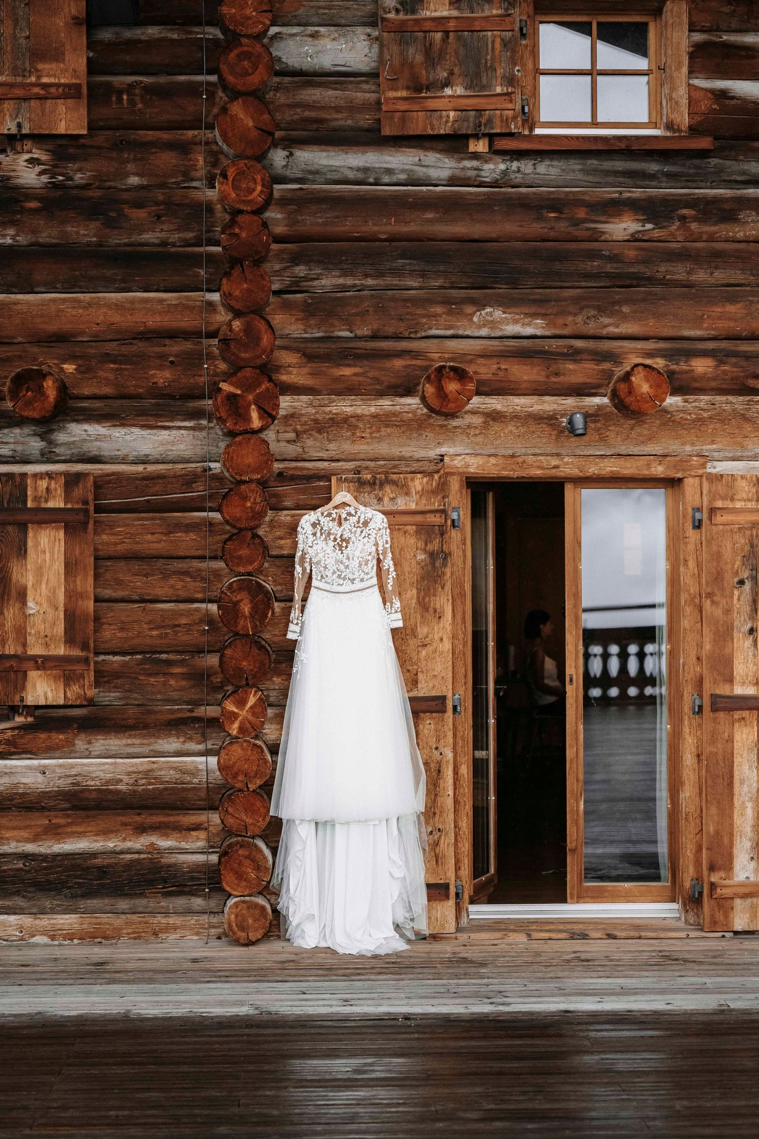 Brautkleid vor rustikaler Holzfassade einer Hochzeitslocation