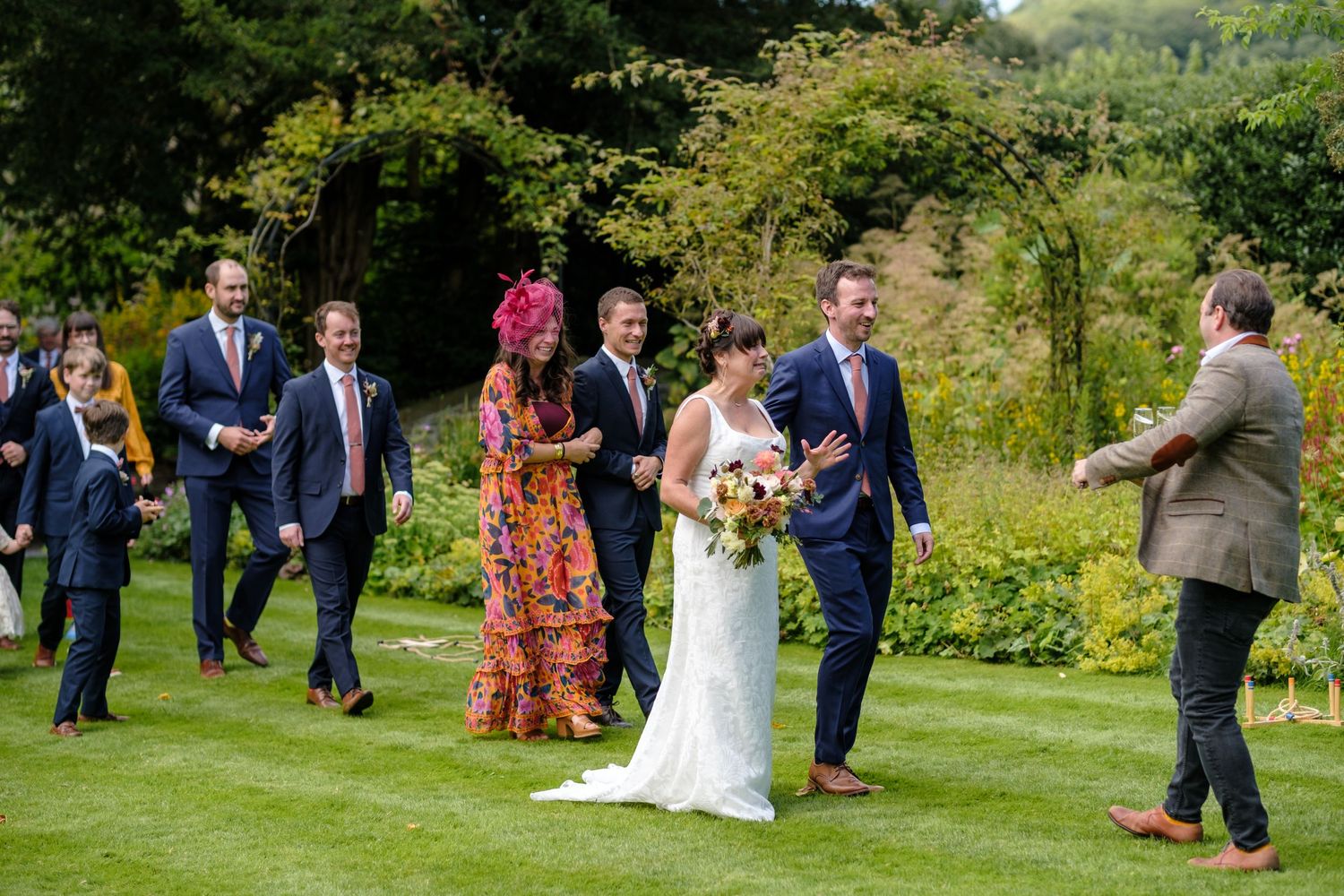 Wide view of an outdoor garden wedding ceremony with guests and natural landscaping. Norfolk and Norwich wedding photographer.
