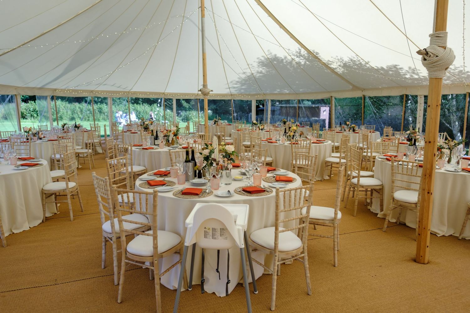 Large wedding reception tent interior with elegantly set round tables and white chairs. Norfolk and Norwich wedding photographer.