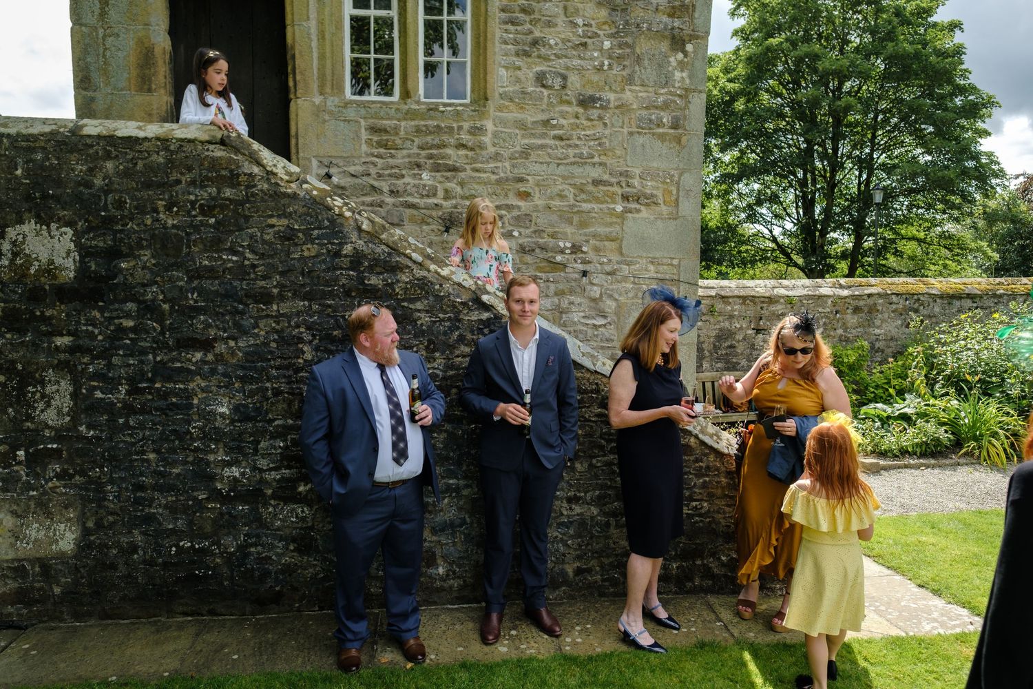 Wedding celebration at historic stone building with guests gathered outside. Norfolk and Norwich wedding photographer.