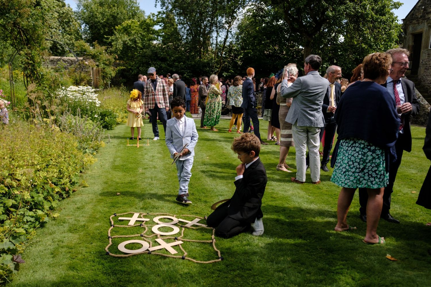 Wedding guests enjoy outdoor festivities on a manicured garden lawn. Norfolk and Norwich wedding photographer.
