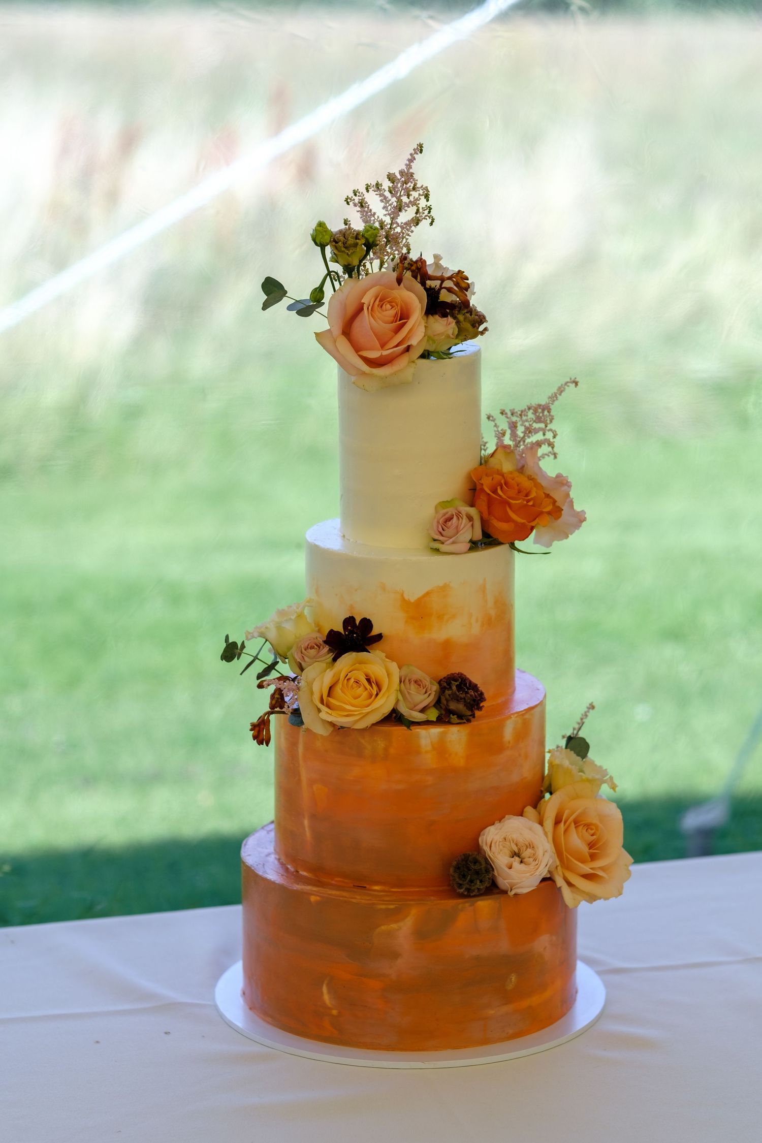 Elegant wedding cake decorated with peach roses and ombre orange watercolour effect. Norfolk and Norwich wedding photographer.