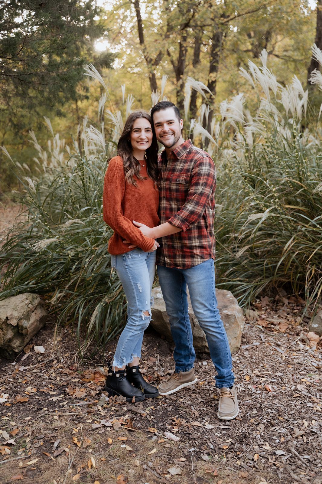 Warm fall portrait by Tulsa photographer featuring smiling couple surrounded by tall grass and autumn colors
