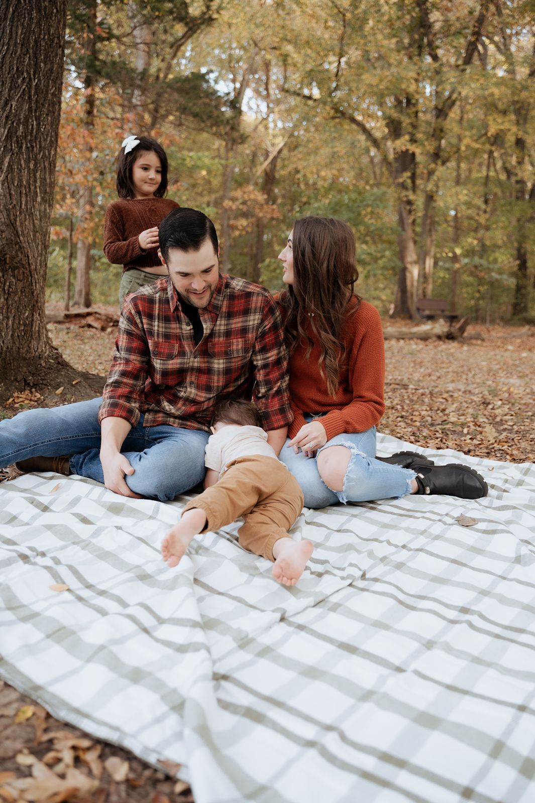 Family hanging out on a picnic blanket on a beautiful fall day for a family photography session