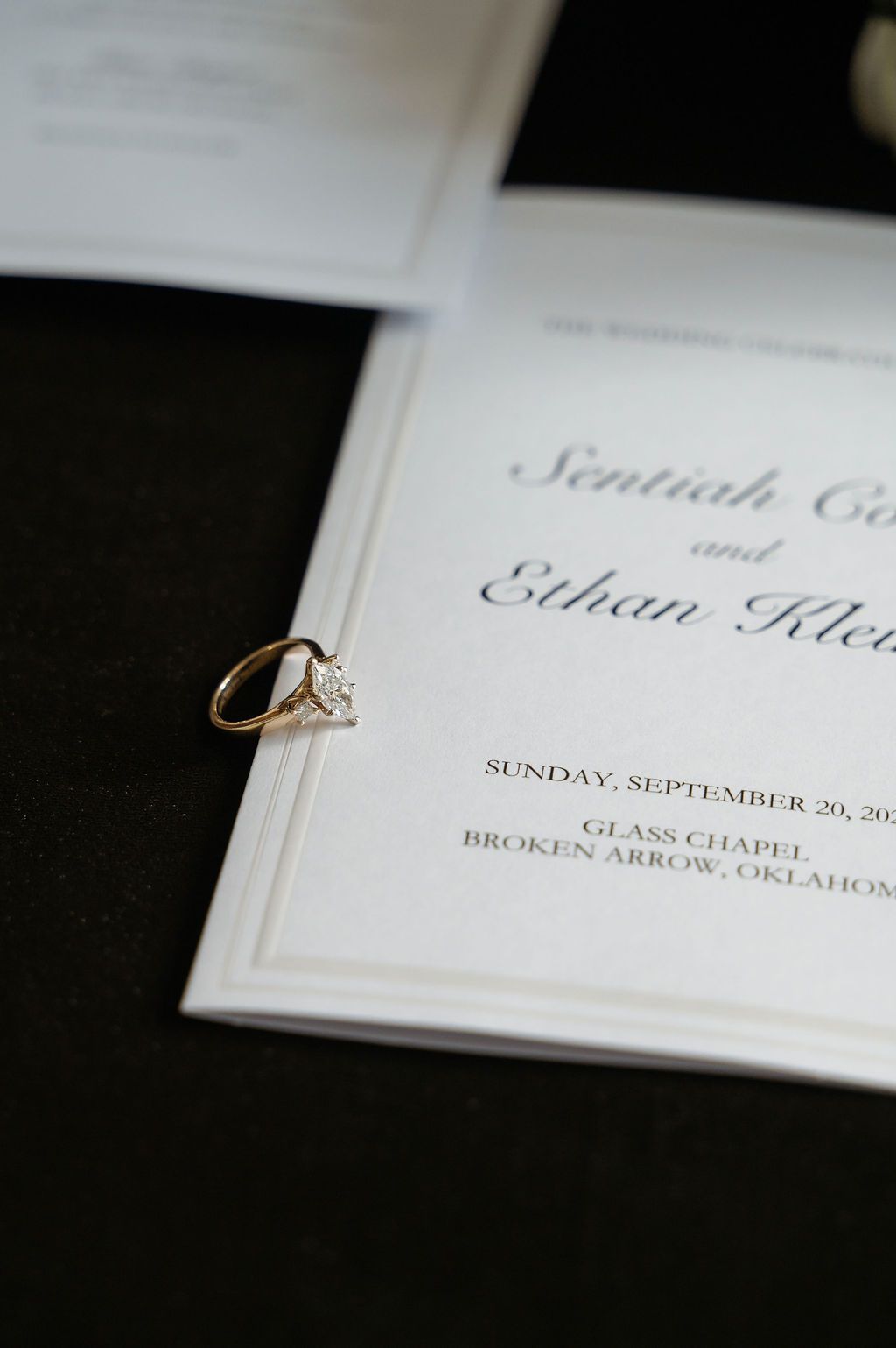 Diamond engagement ring resting on elegant wedding invitation for Ethan Klein at Glass Chapel, Broken Arrow, Oklahoma, September 20.