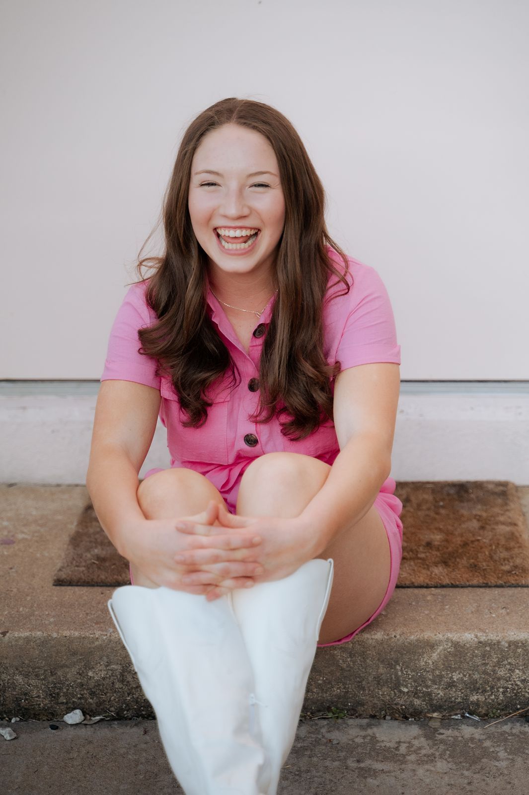 Girl in a pink romper with white boots laughing