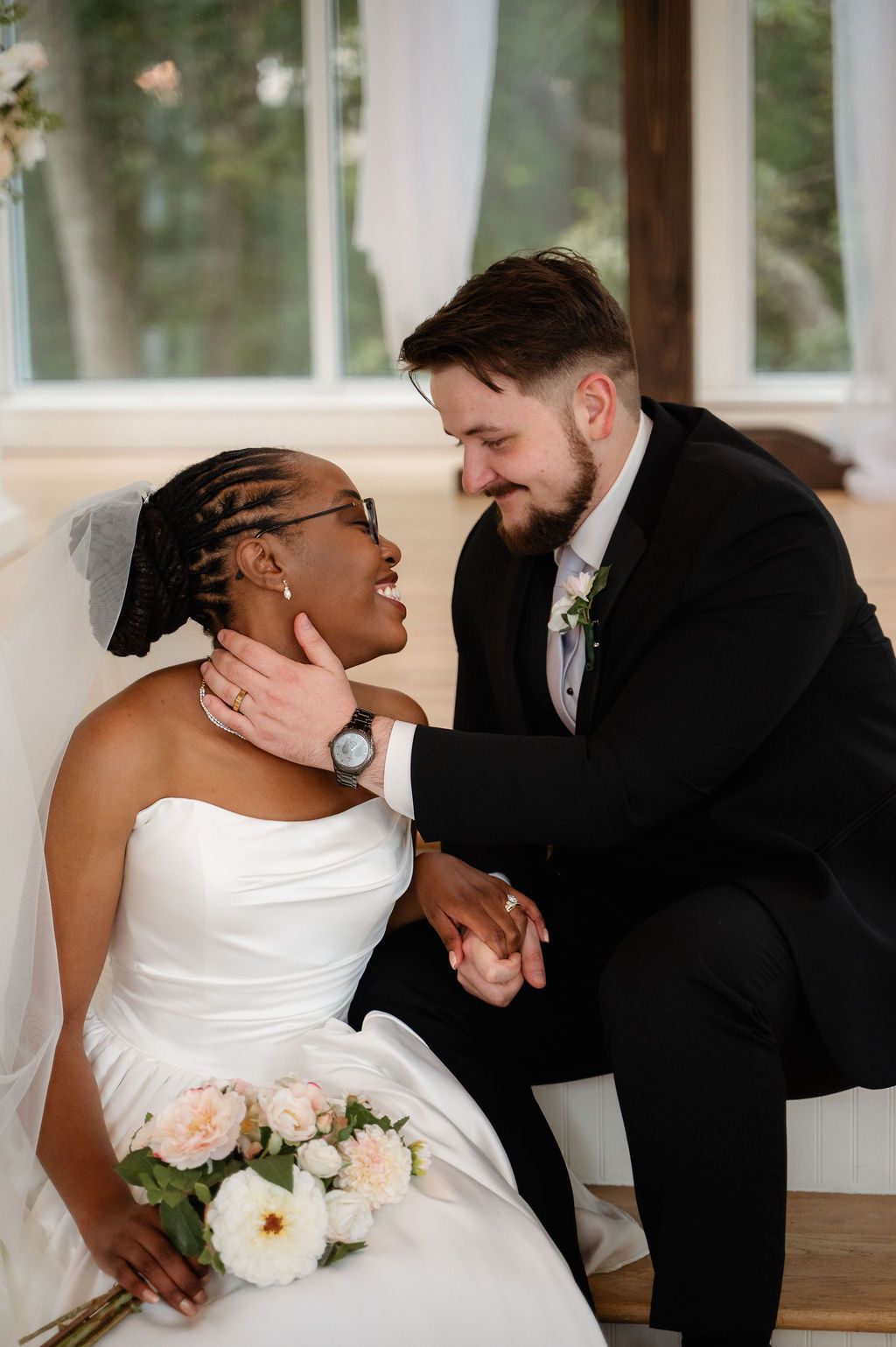 Groom tenderly holds bride's face as they share an intimate moment on their wedding day.