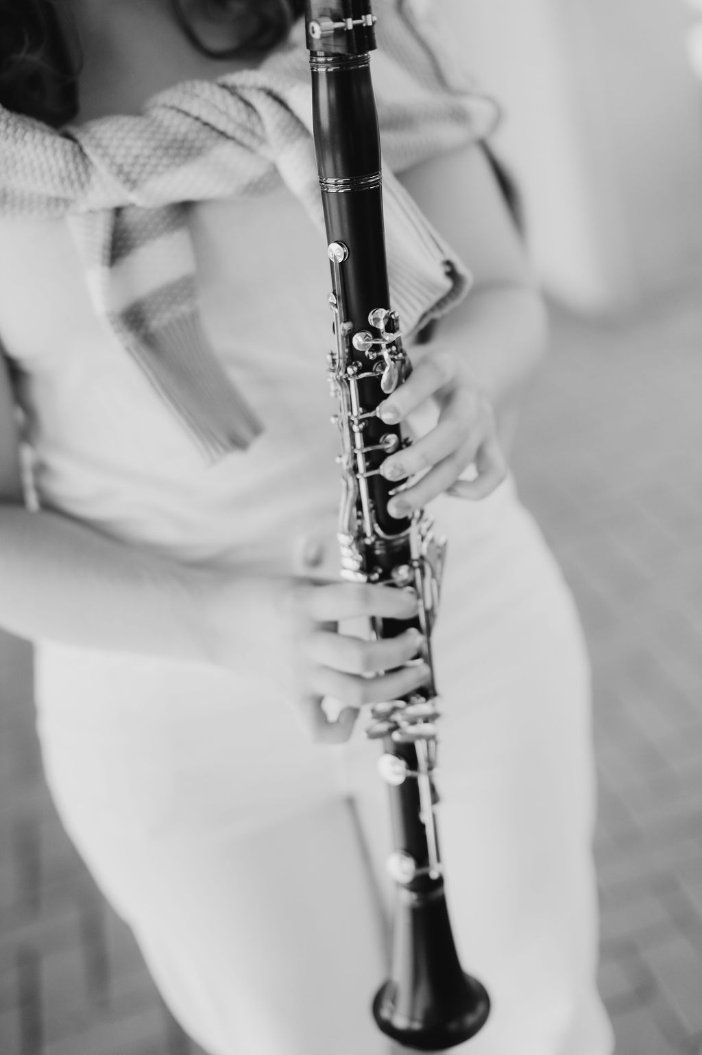 Close-up black and white photo of young musician holding a clarinet during senior portrait session.