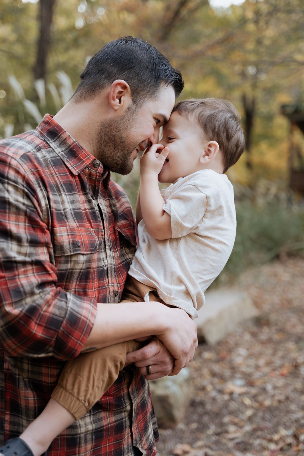 Tulsa family photographer capturing candid father and toddler moment during cozy fall family session outdoors