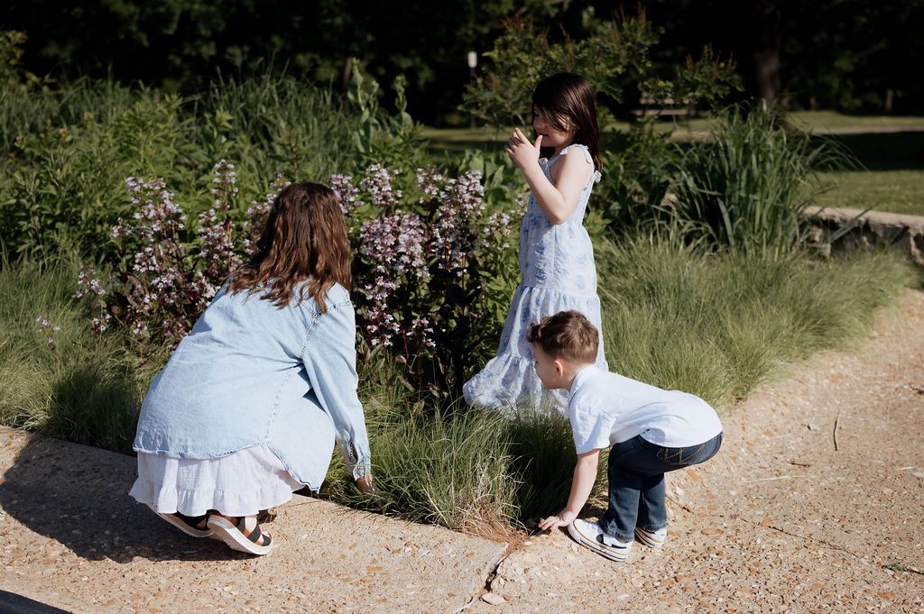 Natural motherhood photography of a mom and her children exploring flowers in a Tulsa park