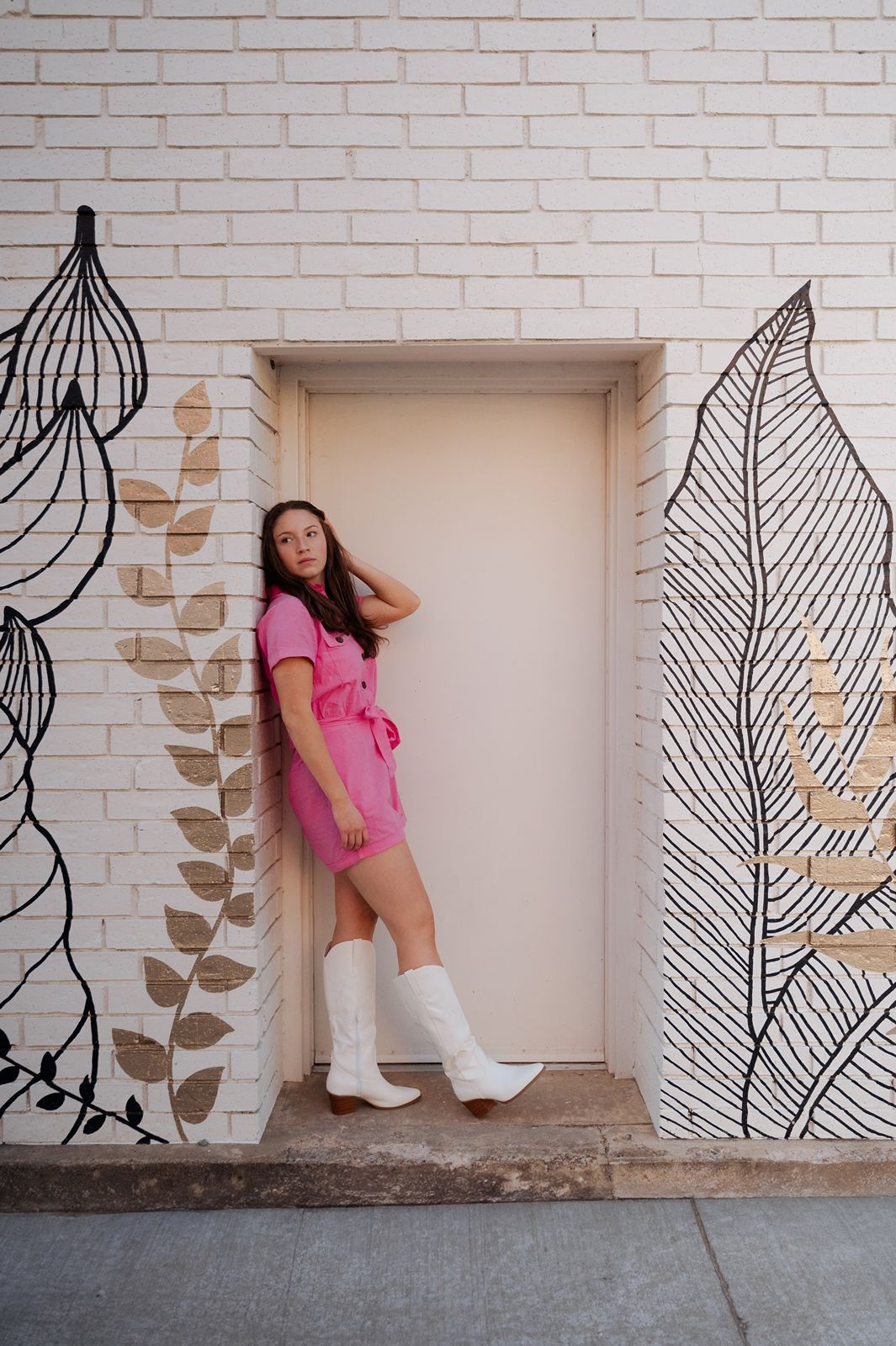 girl in a pink outfit and white boots posing in a door frame