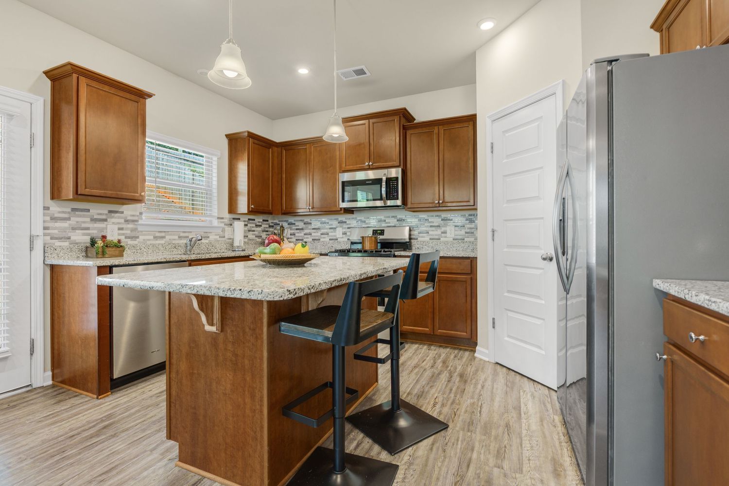 Modern kitchen with wood cabinets, granite countertops, and stainless steel appliances.