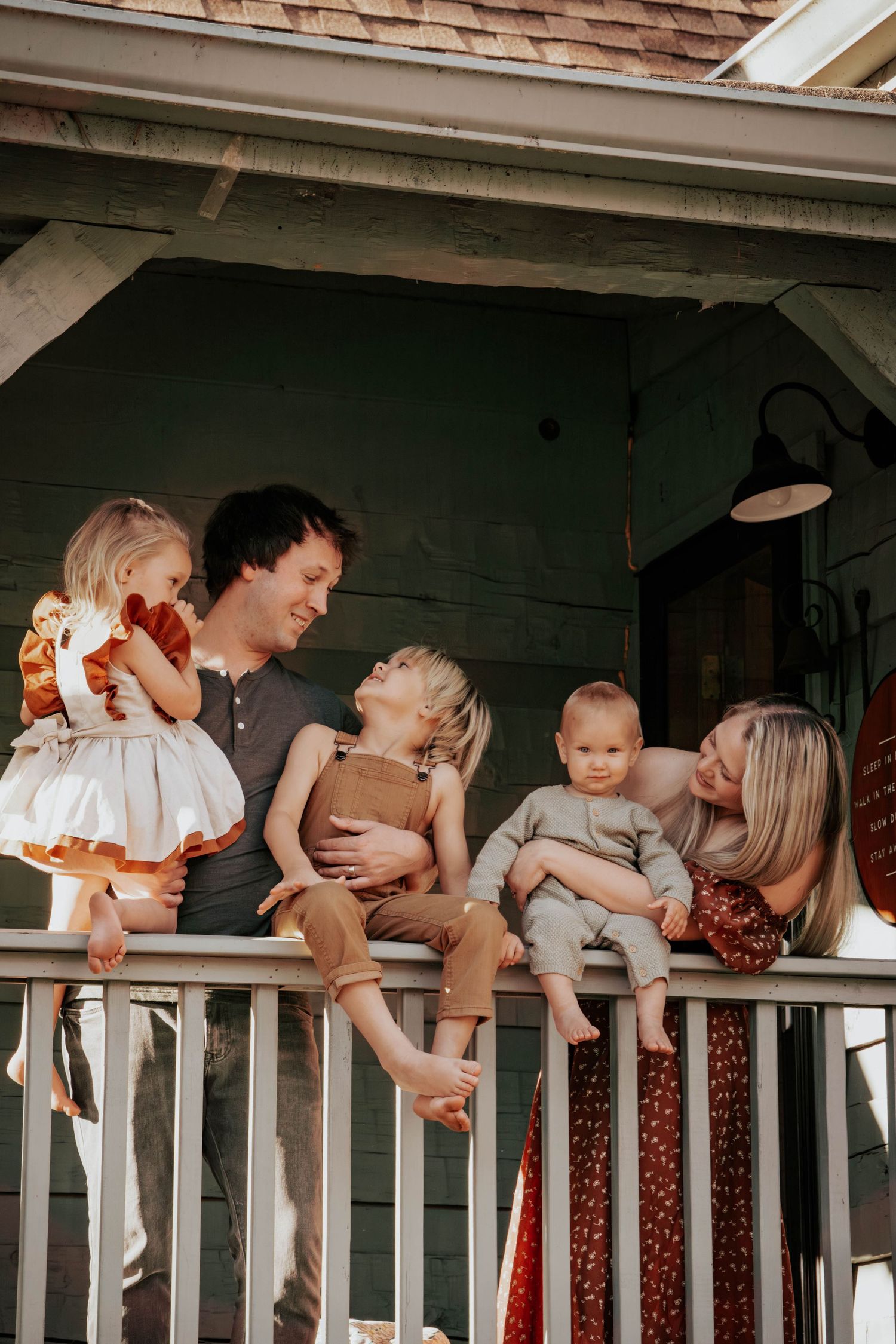 Creative family photo of people lounging on white porch railings.