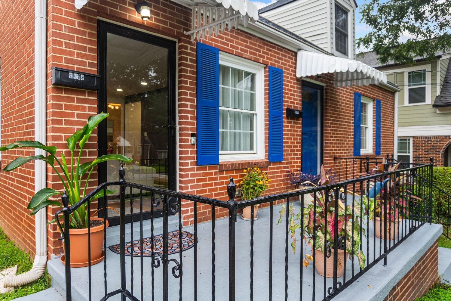 A row of brick townhouses with black metal railings and blue trim along their front porches.