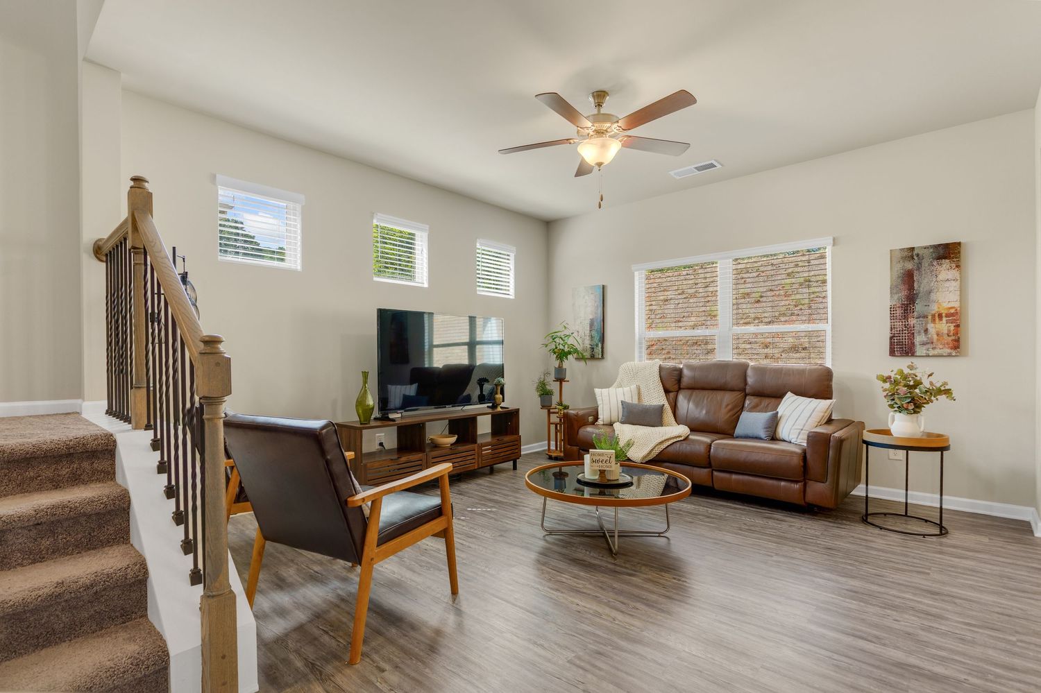 Modern living room interior with cream couch, wooden floors, and ceiling fan showing clean contemporary design.