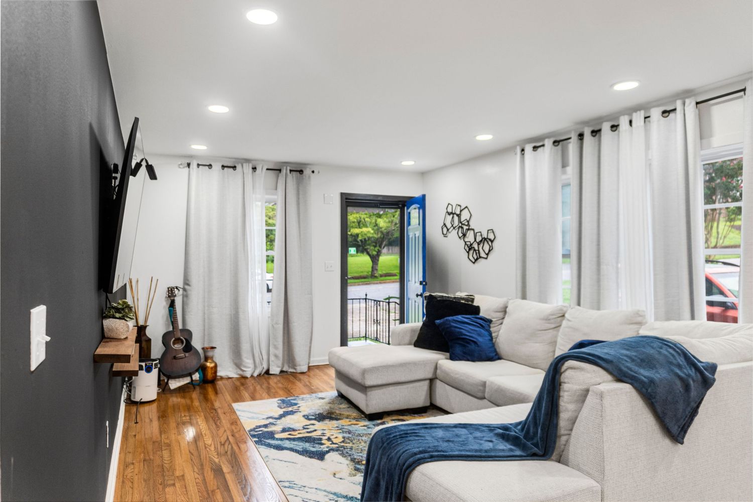 Modern apartment interior featuring hardwood floors, white walls, and multiple rooms with contemporary furnishings.