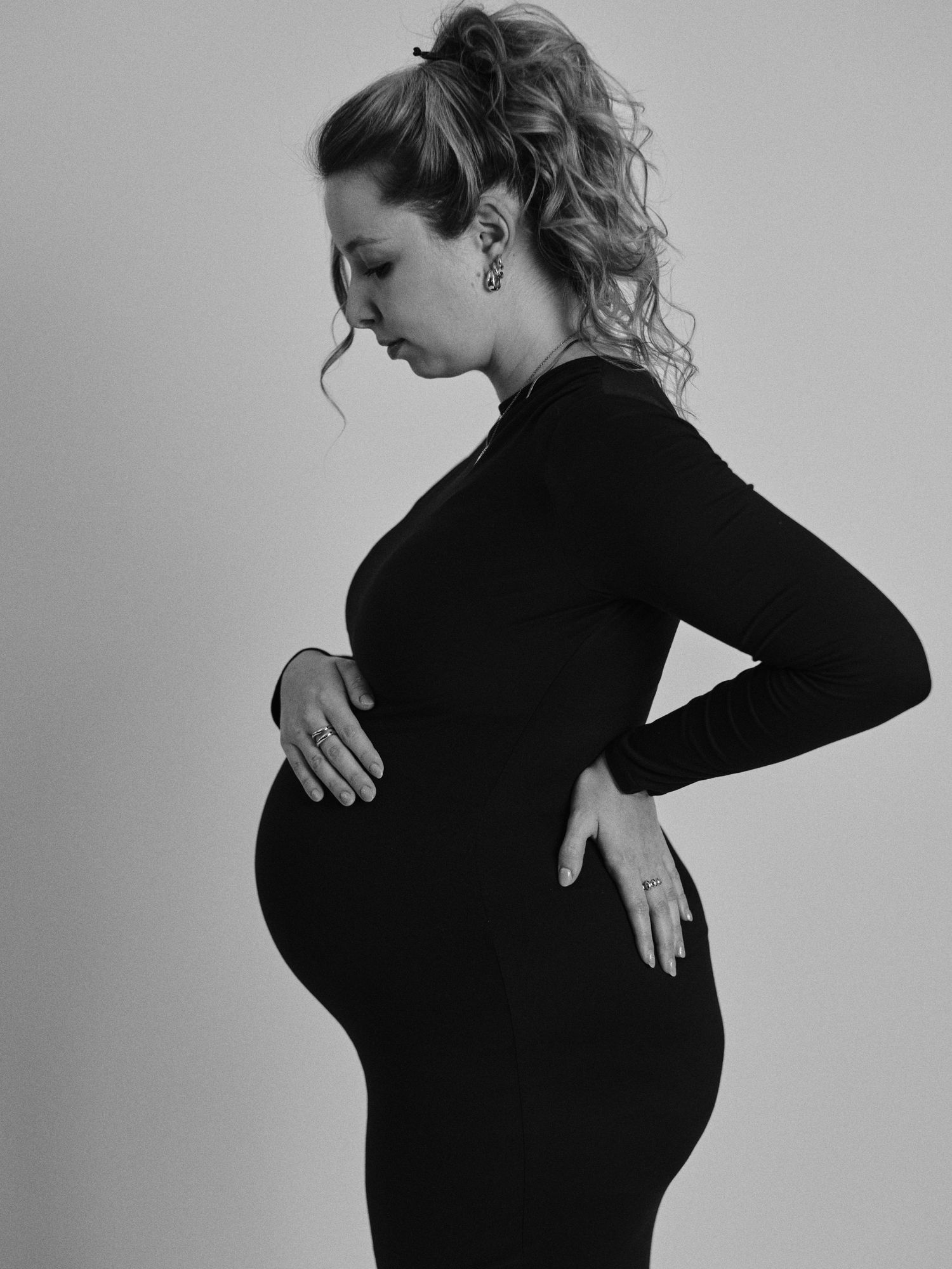 Black and white artistic photo series showing a woman in black attire posing against a light background.